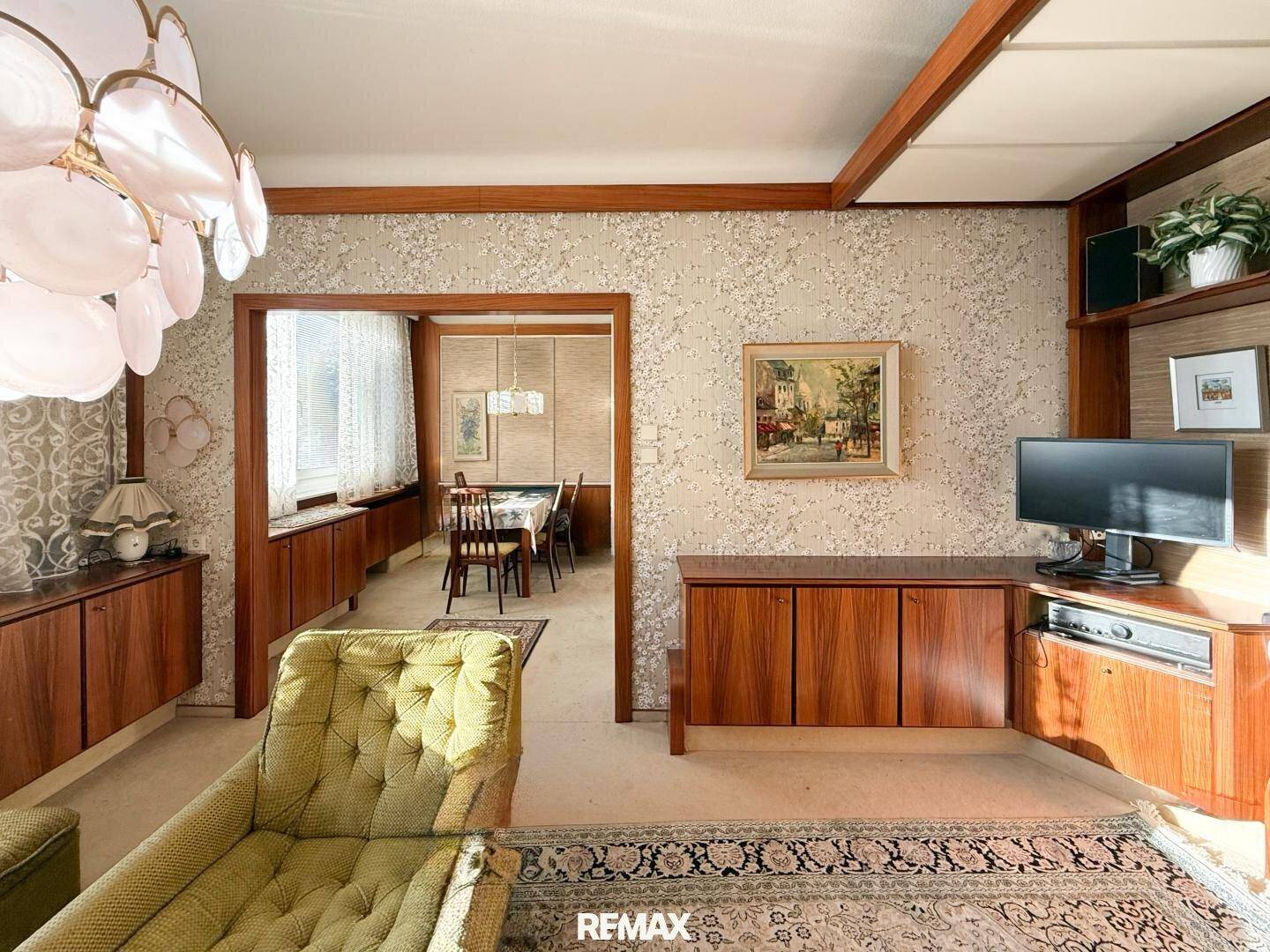 Wohnzimmer im Vintage-Stil mit grünen Möbeln und Blick in den angrenzenden Essbereich.