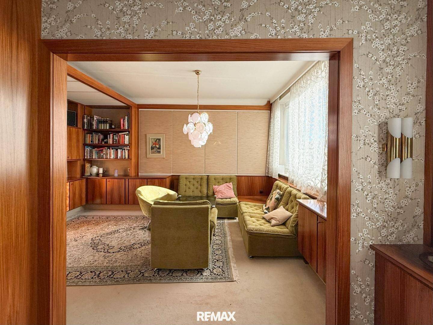 Gemütliches Wohnzimmer mit umfangreichen Holzvertäfelungen, Bücherregalen und floraler Tapete.