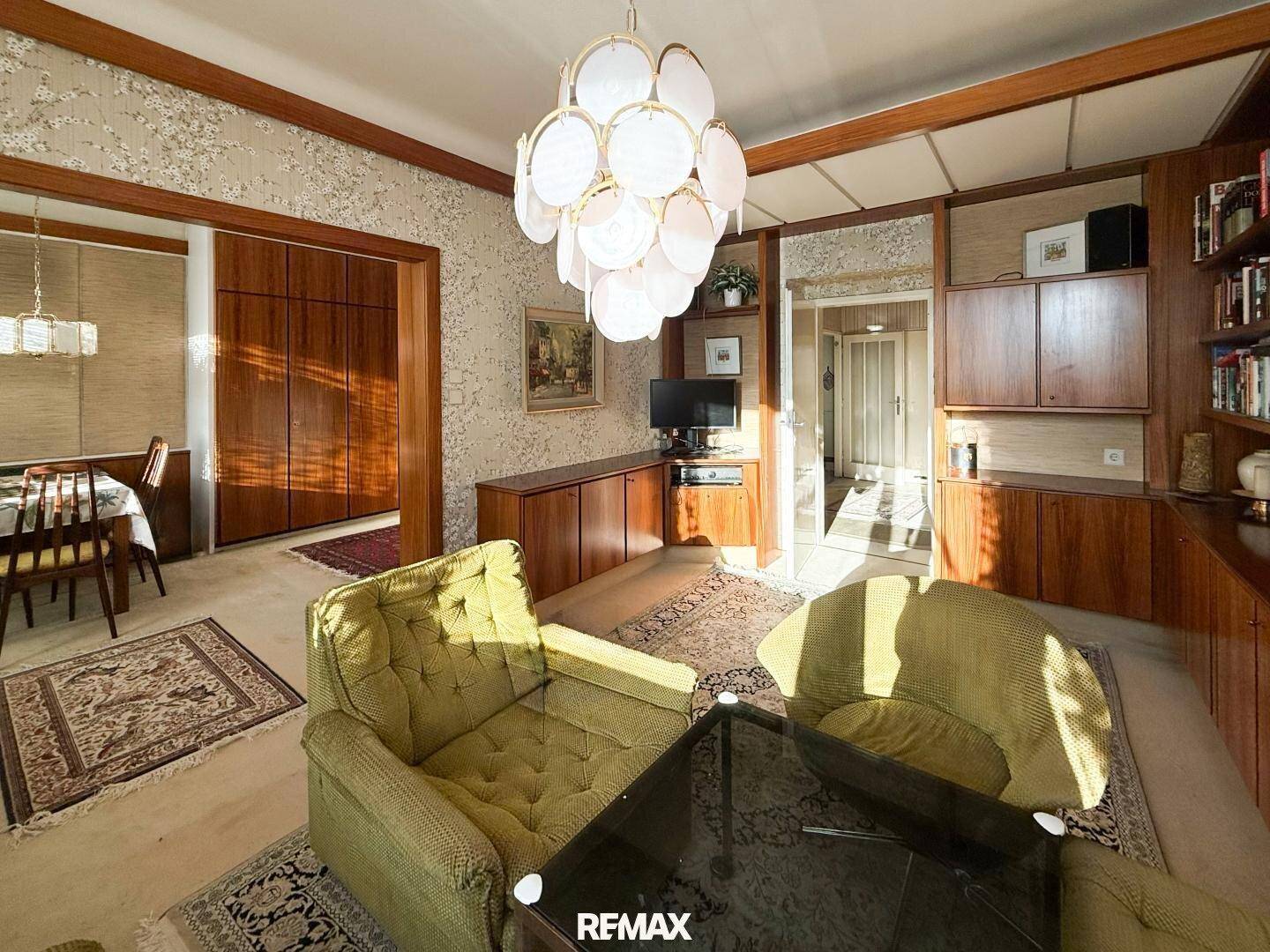 Geräumiges Wohnzimmer im Vintage-Stil mit grünen Sesseln und Blick in den Flur.