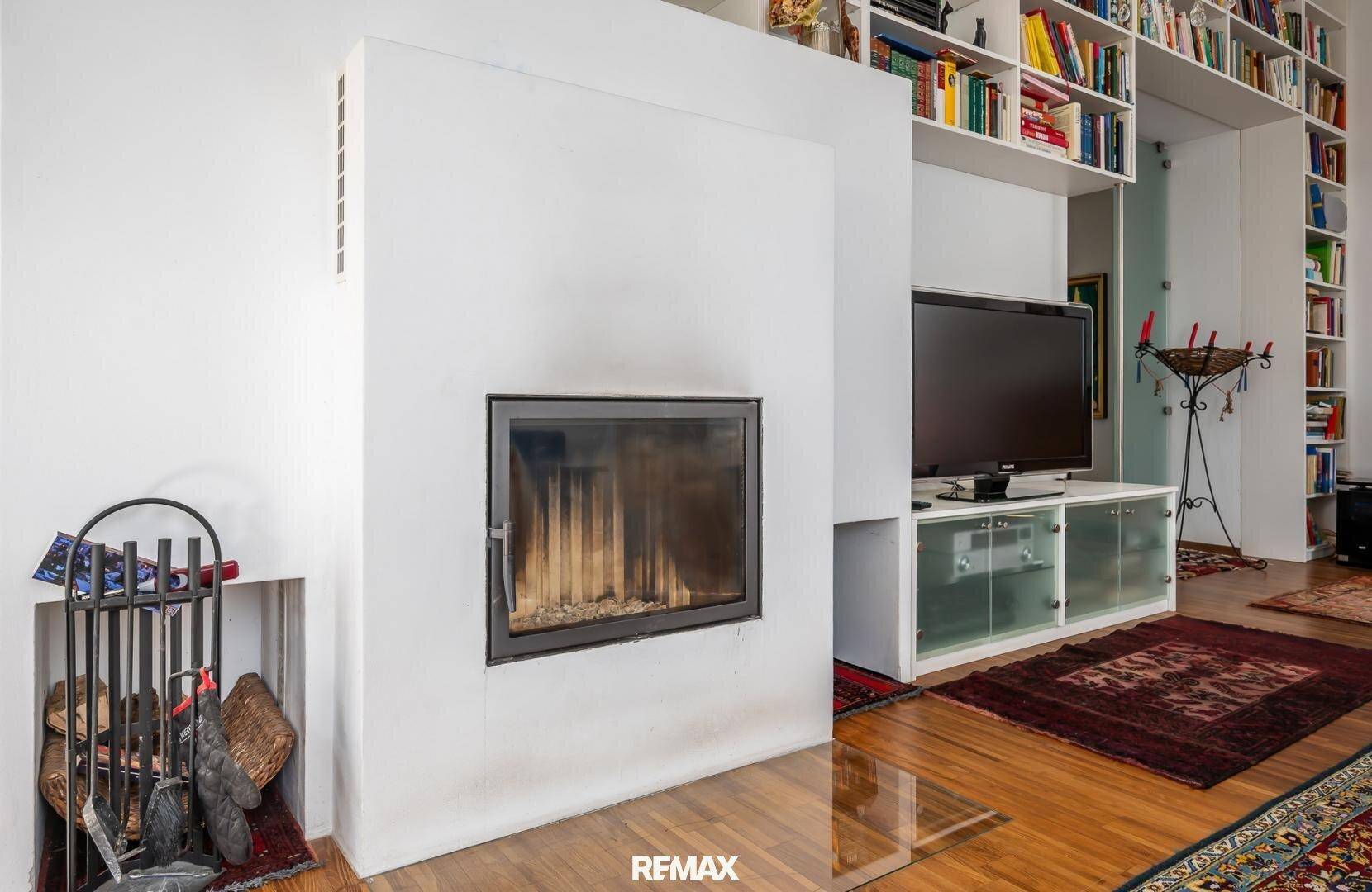 Moderner Kamin als zentrales Element im Wohnzimmer, umgeben von praktischen Einbauregalen.