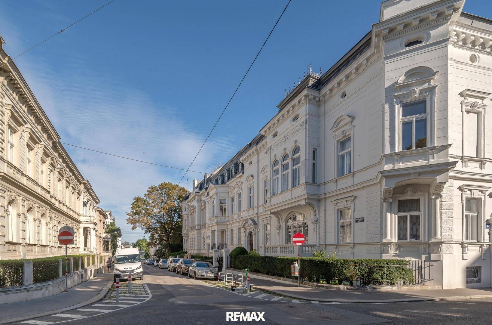 Elegante Straße mit historischen weißen Gebäuden, die eine klassische und gepflegte Atmosphäre schaffen.