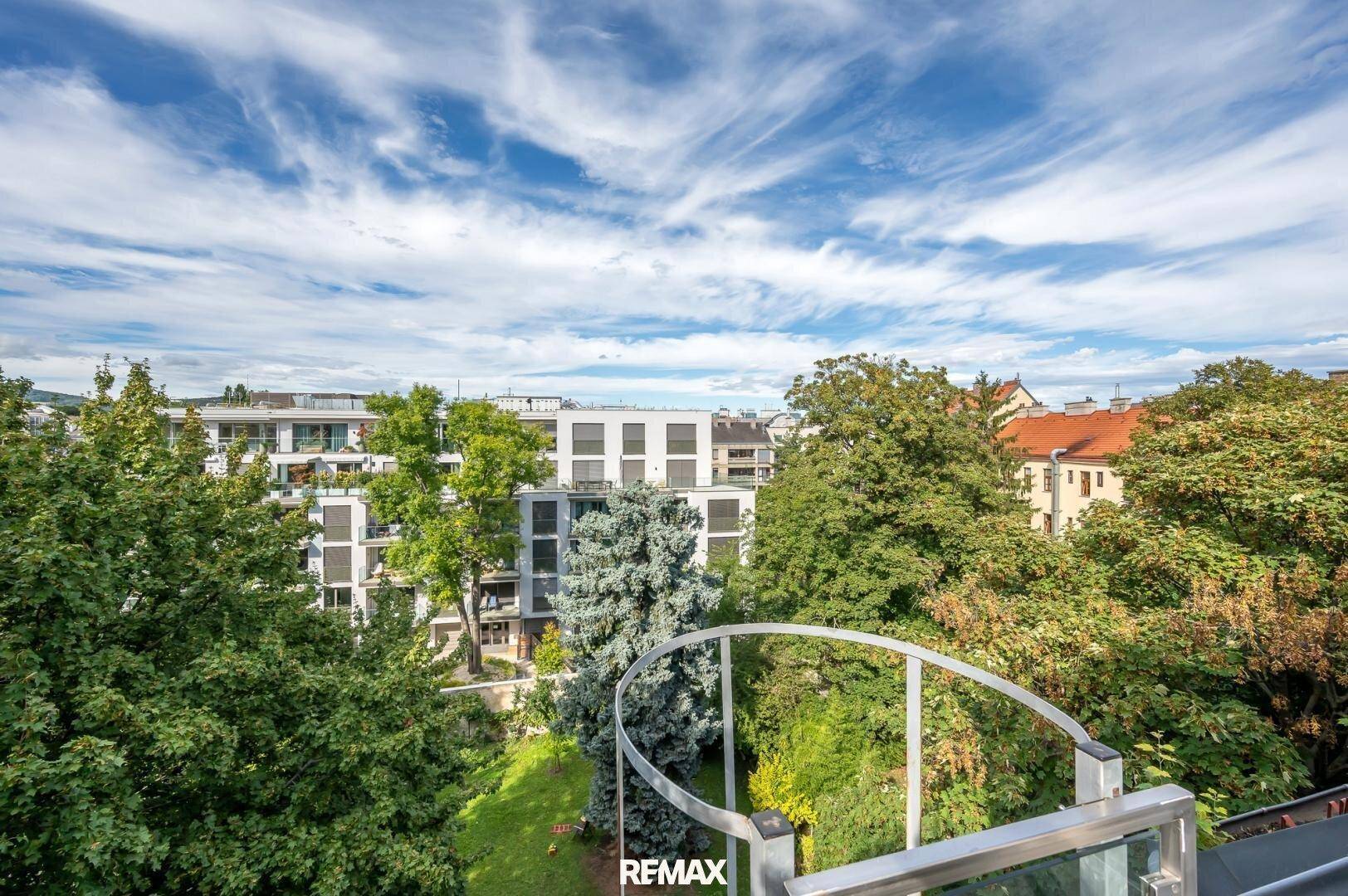 Weitblick über grüne Bäume und Wohngebäude unter einem strahlend blauen Himmel.