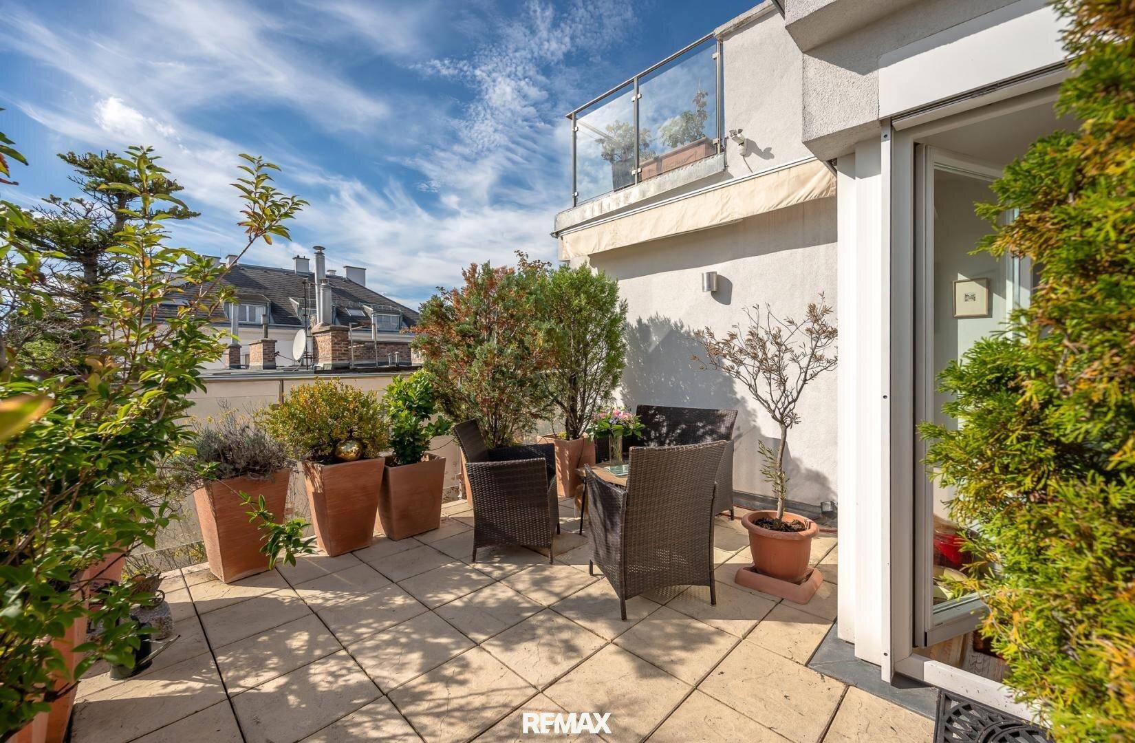 Gemütliche Terrasse mit Sitzgelegenheiten und Pflanzen, ideal für entspannte Stunden im Freien.