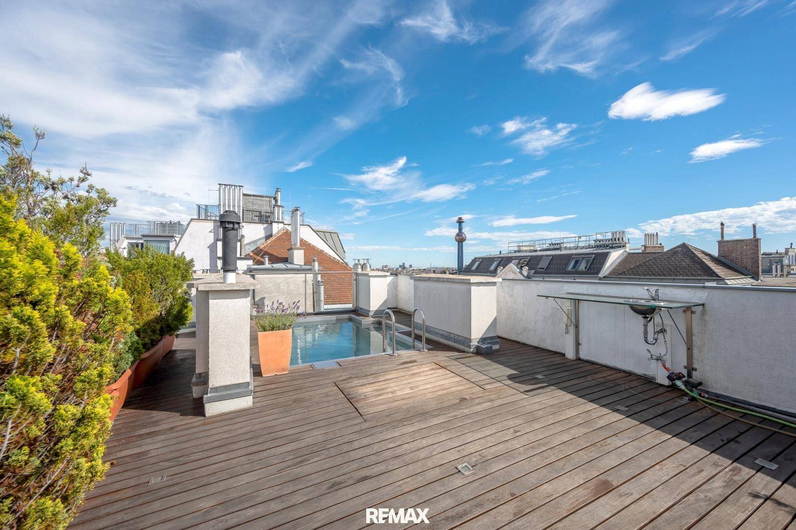 Exklusive Dachterrasse mit kleinem Pool, Holzdeck und weitem Blick über die Dächer der Stadt.