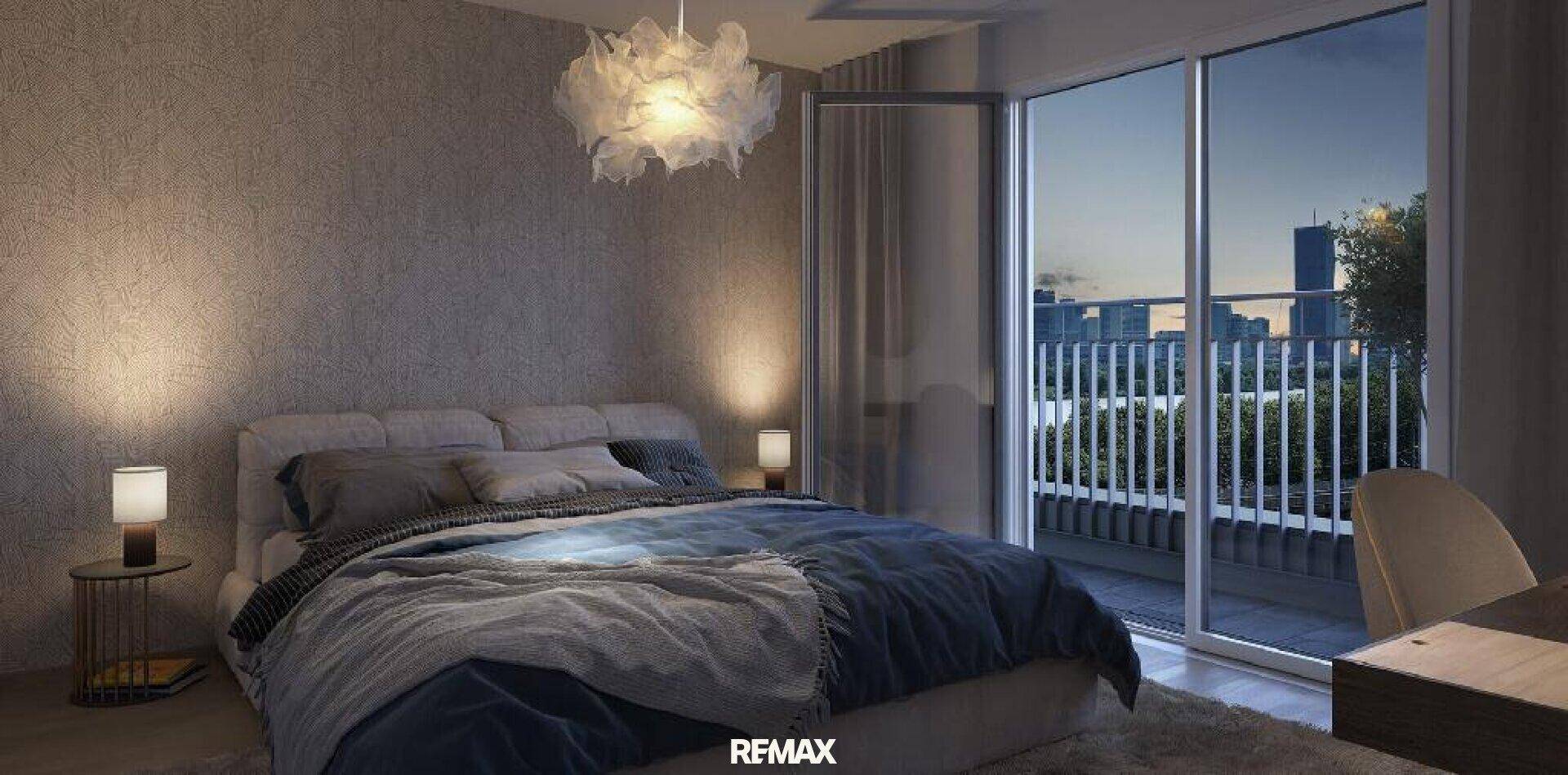Gemütliches Schlafzimmer mit Balkonzugang und Blick auf die Stadt bei Abenddämmerung.