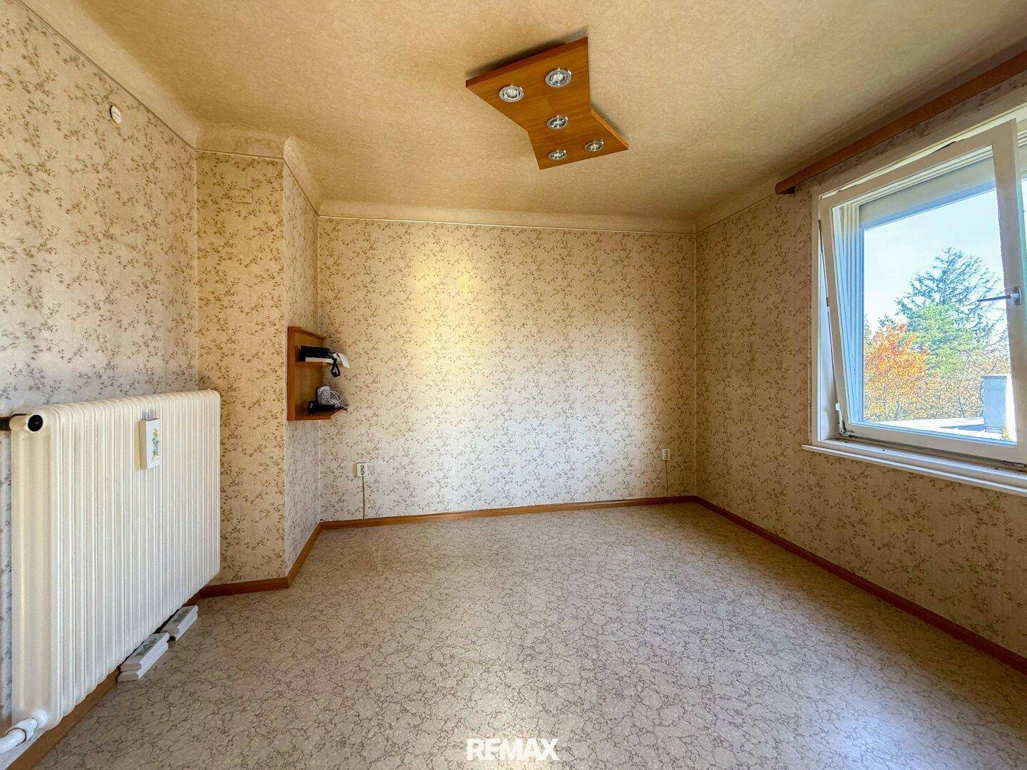Zimmer mit Korkboden, Heizkörper und Fenster, bereit für individuelle Gestaltung und Nutzung.