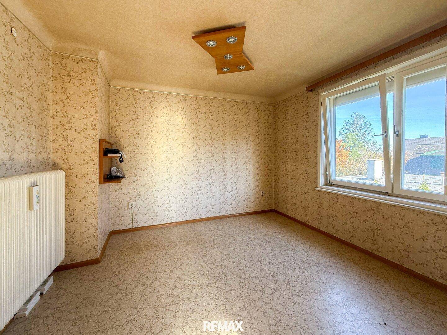 Helles Zimmer mit Korkboden und großem Fenster, das viel Sonnenlicht bietet und den Raum erhellt.