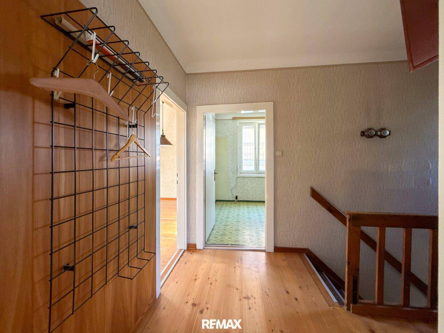 Heller Flur mit Holzfußboden und Garderobe, der zu weiteren Zimmern und Treppen führt.