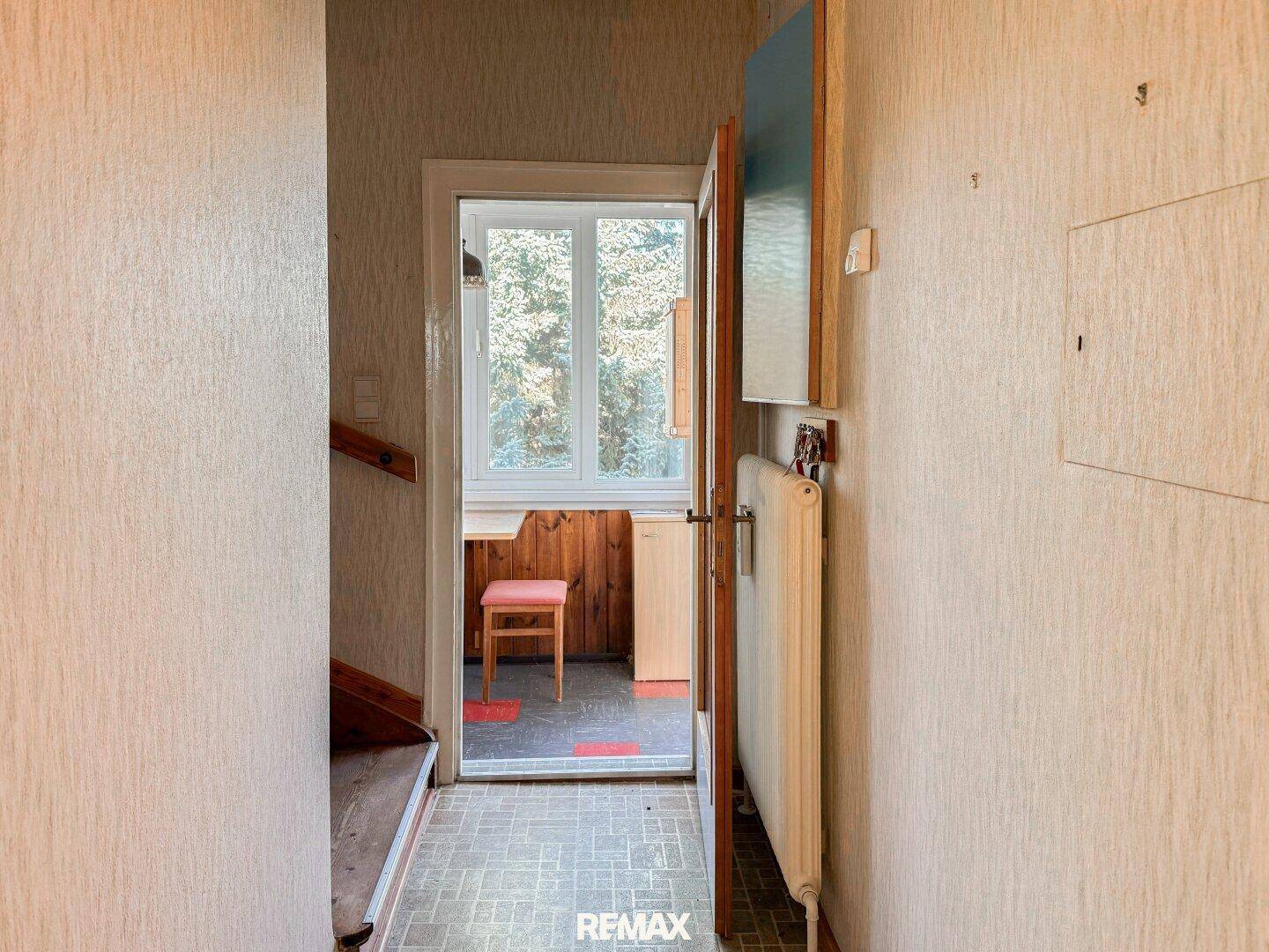 Flur mit Zugang zu einem hellen Raum mit Holzverkleidung und Fenster, der viel Tageslicht bietet.