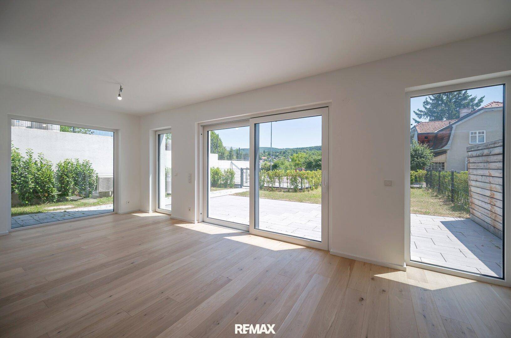 Geräumiges Wohnzimmer mit Eichenparkett und großen Schiebetüren zur Terrasse und zum Garten.