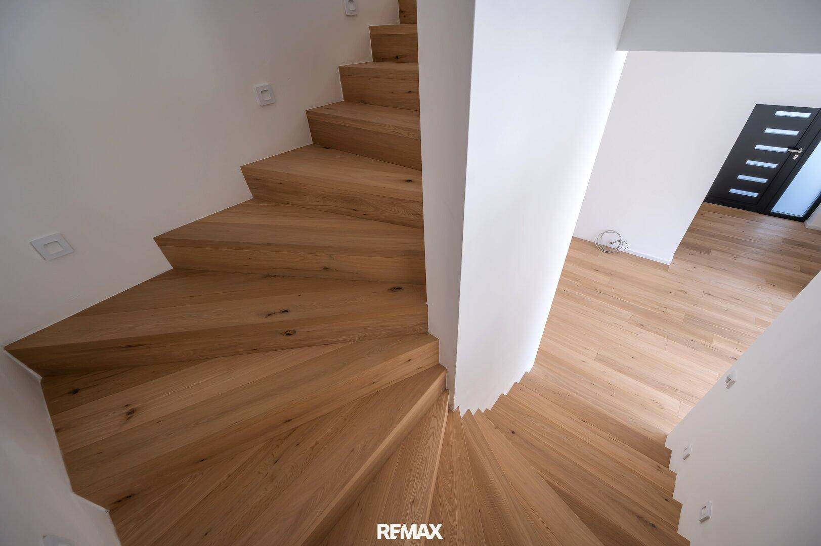 Elegante Holztreppe mit Eichenstufen, die die verschiedenen Ebenen des Hauses stilvoll verbindet.