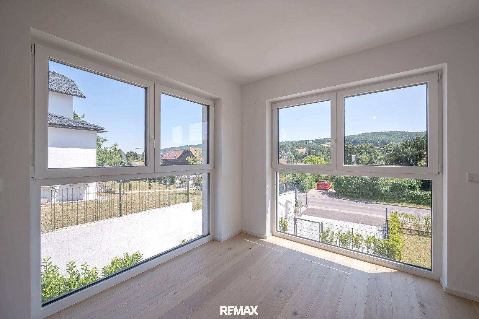Helles Schlafzimmer mit Eichenparkettboden und großen Fenstern, die einen weiten Blick auf die Landschaft bieten.