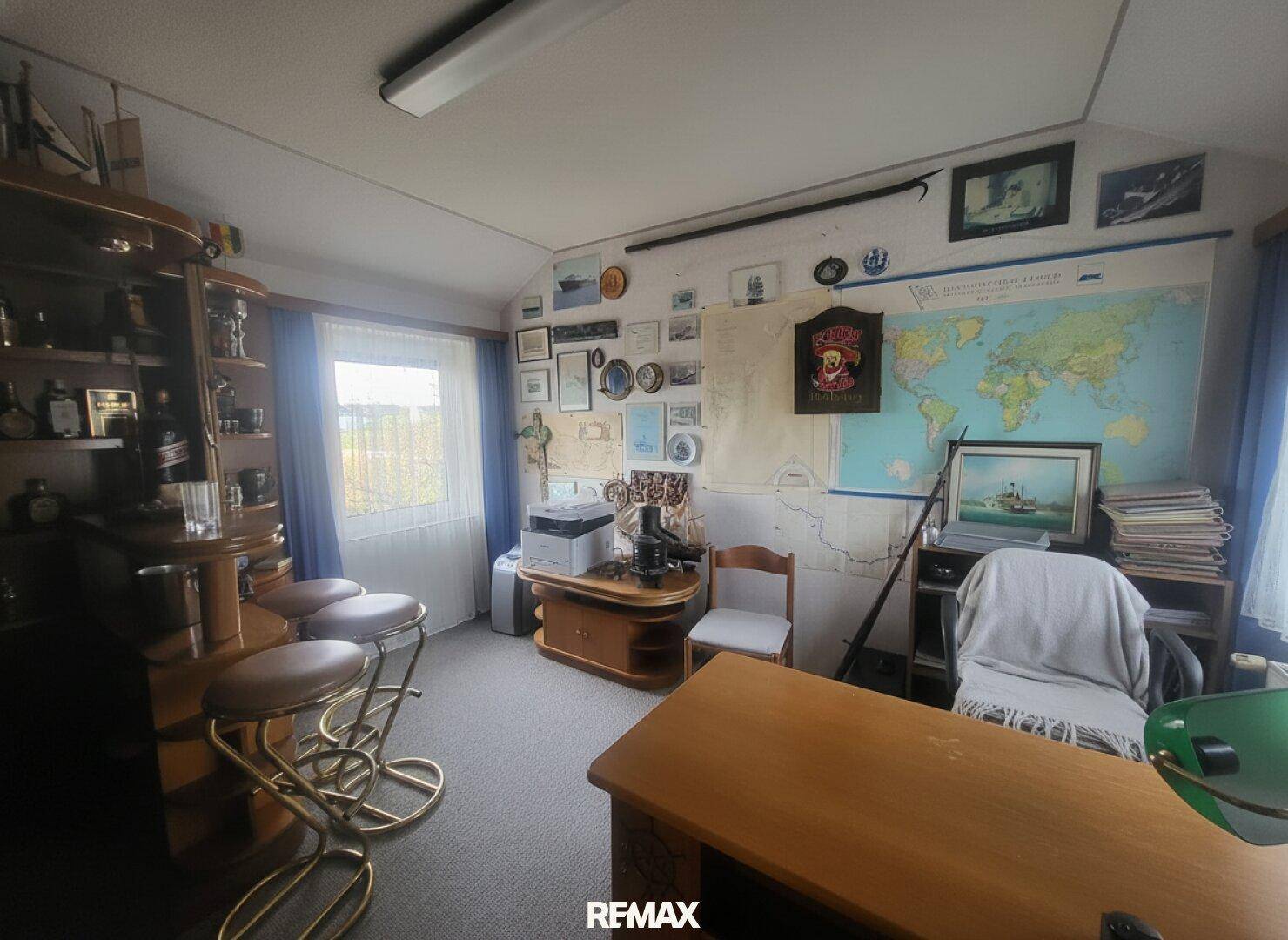Arbeitszimmer mit Teppichboden, Weltkarte an der Wand und rustikalen Möbeln.