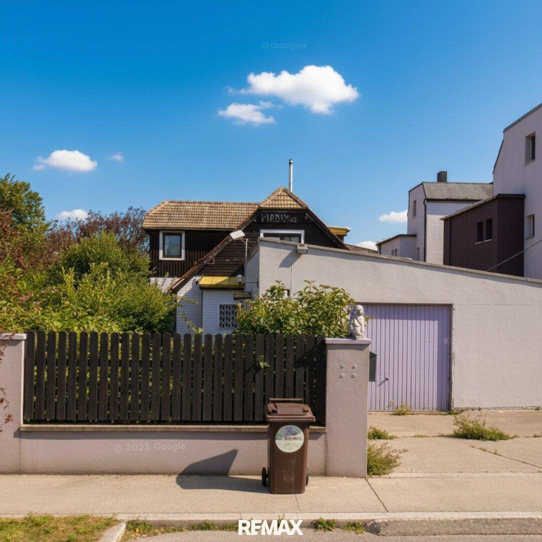Straßenansicht des Hauses mit Zaun, Garage und Mülltonnen.