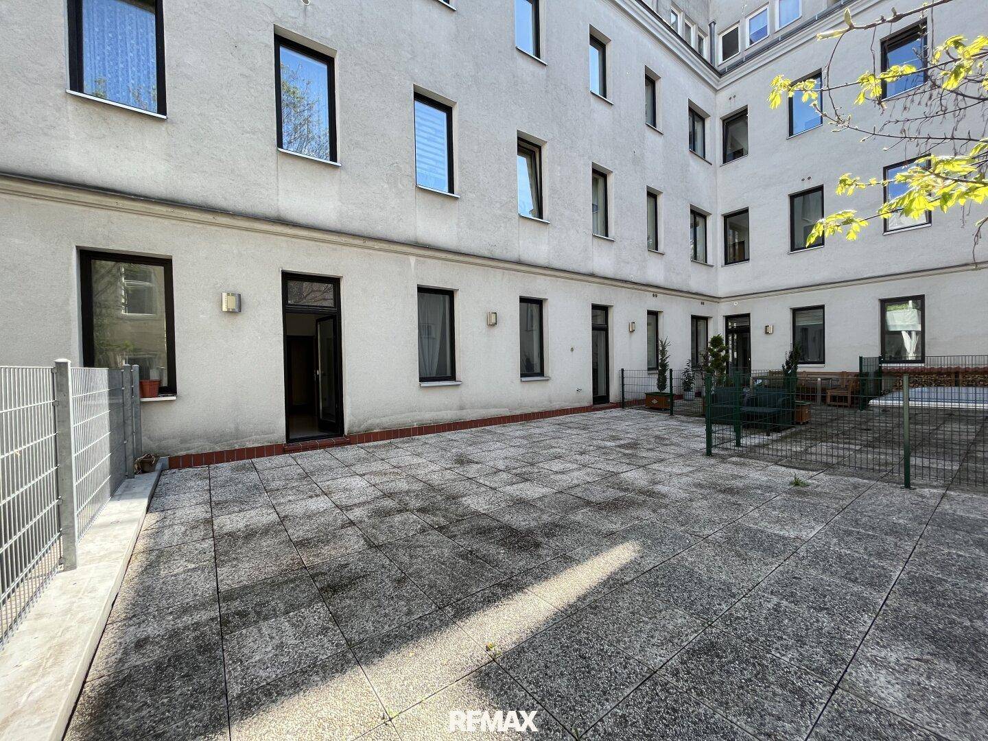 Große gepflasterte Terrasse im Innenhof mit Sitzgelegenheiten und Blick auf die umliegenden Gebäude.