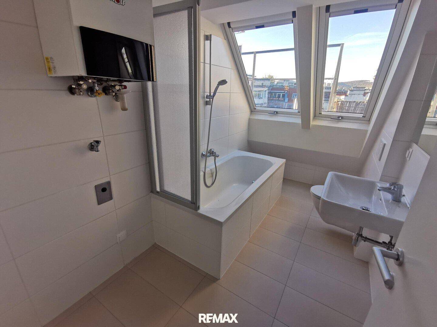 Helles Badezimmer mit Badewanne, Duschabtrennung, WC und Waschbecken unter schrägen Dachfenstern.