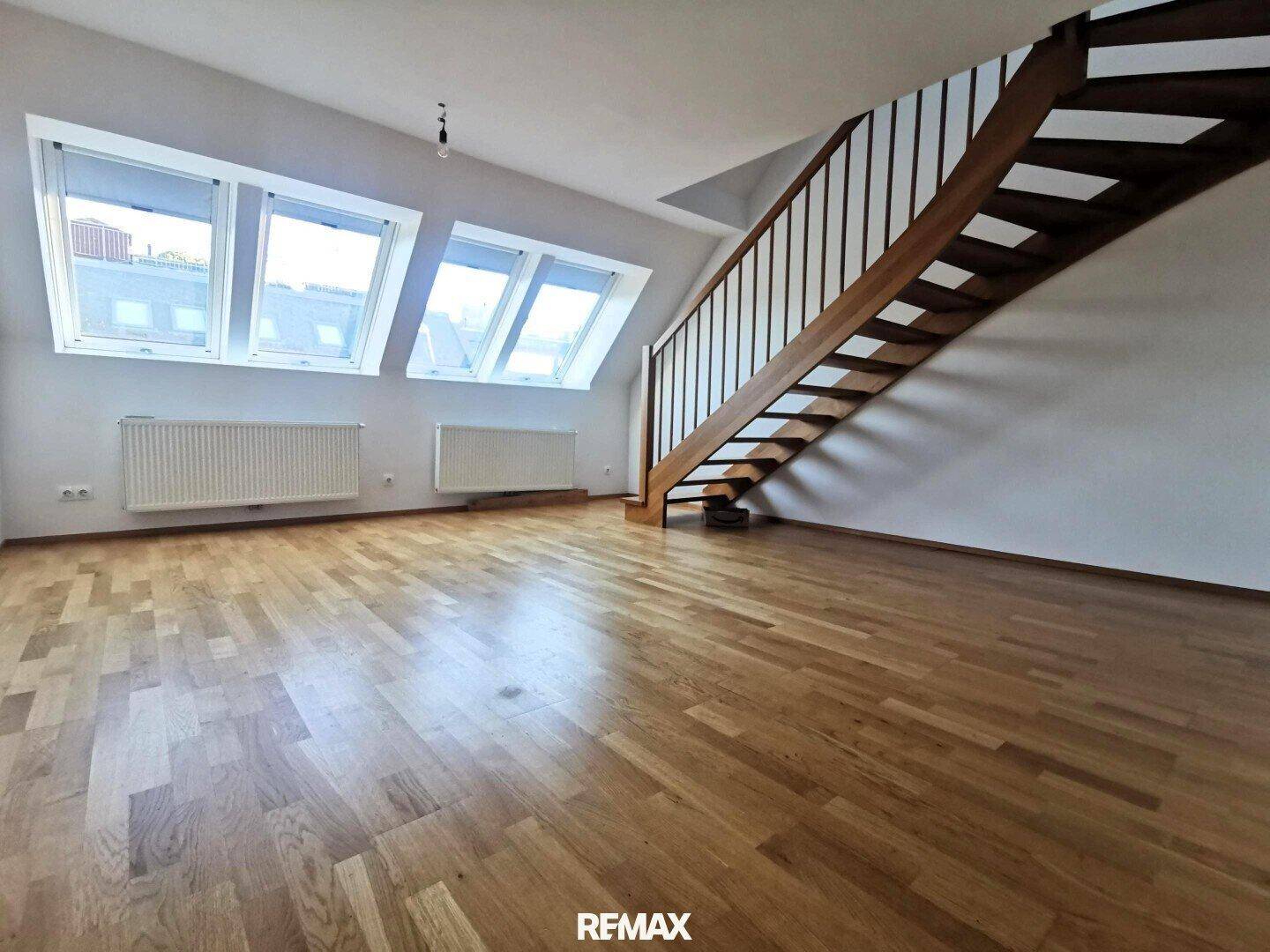 Großzügiger Wohnbereich mit Holztreppe, Parkettboden und mehreren Dachfenstern für viel Licht.