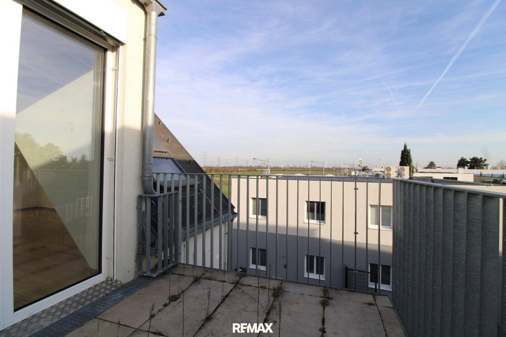 Geräumiger Balkon mit Blick auf die weite Landschaft und die benachbarten Gebäude.