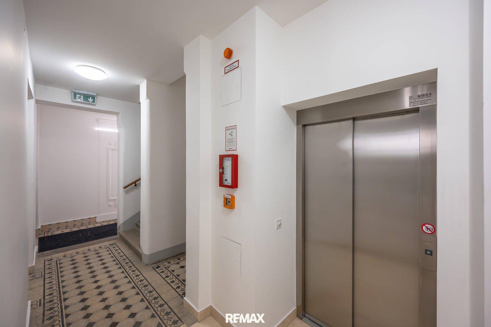 Heller Flur im Gebäude mit Aufzug und Zugang zum Treppenhaus.