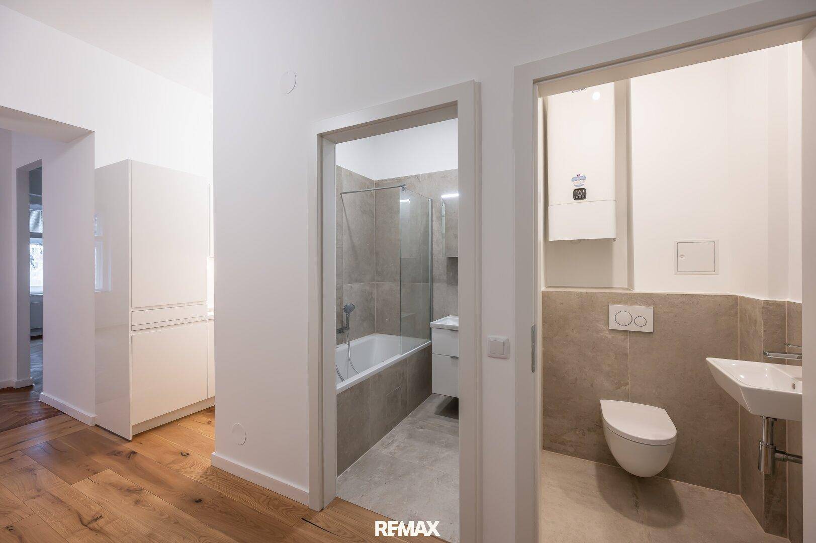 Blick in ein modernes Badezimmer mit Badewanne und separatem WC-Bereich.