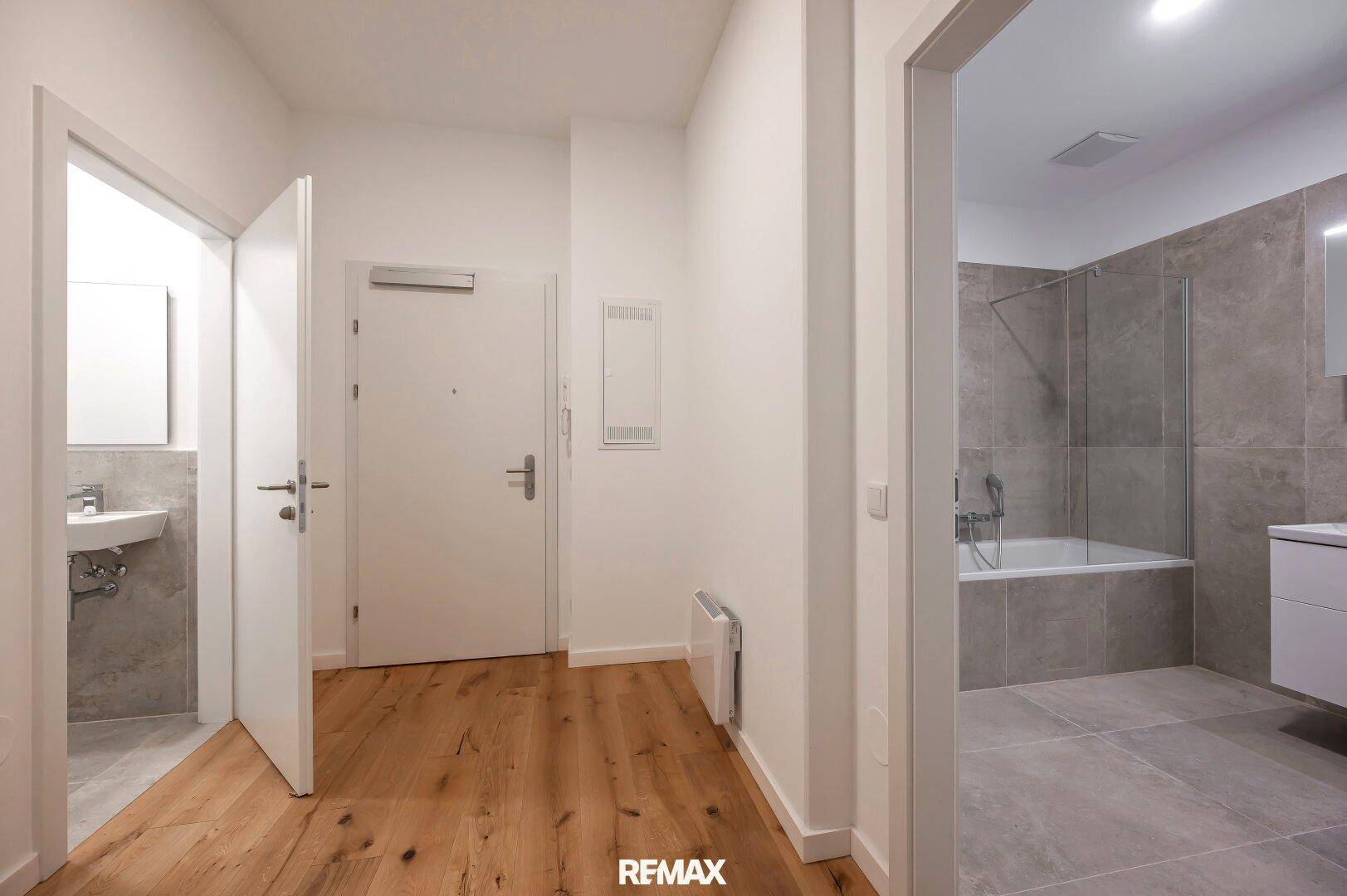 Eingangsbereich mit Holzboden, der zu einem Badezimmer und einer Gästetoilette führt.