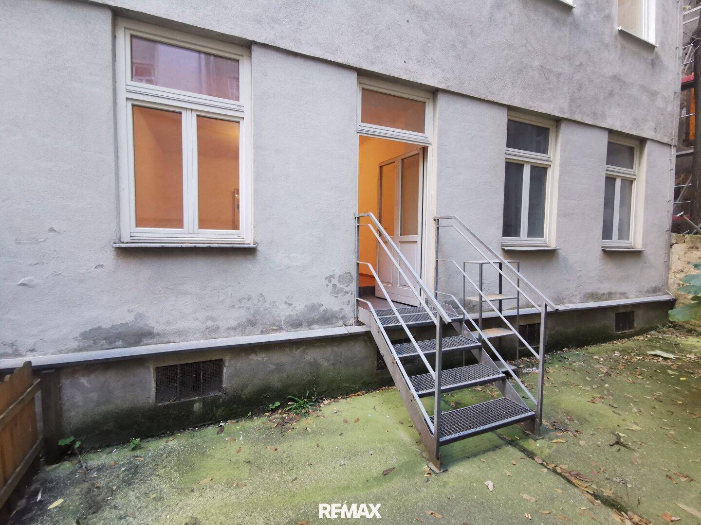 Rückseite eines Gebäudes mit Außentreppe, die zu einem Eingang im Erdgeschoss führt.
