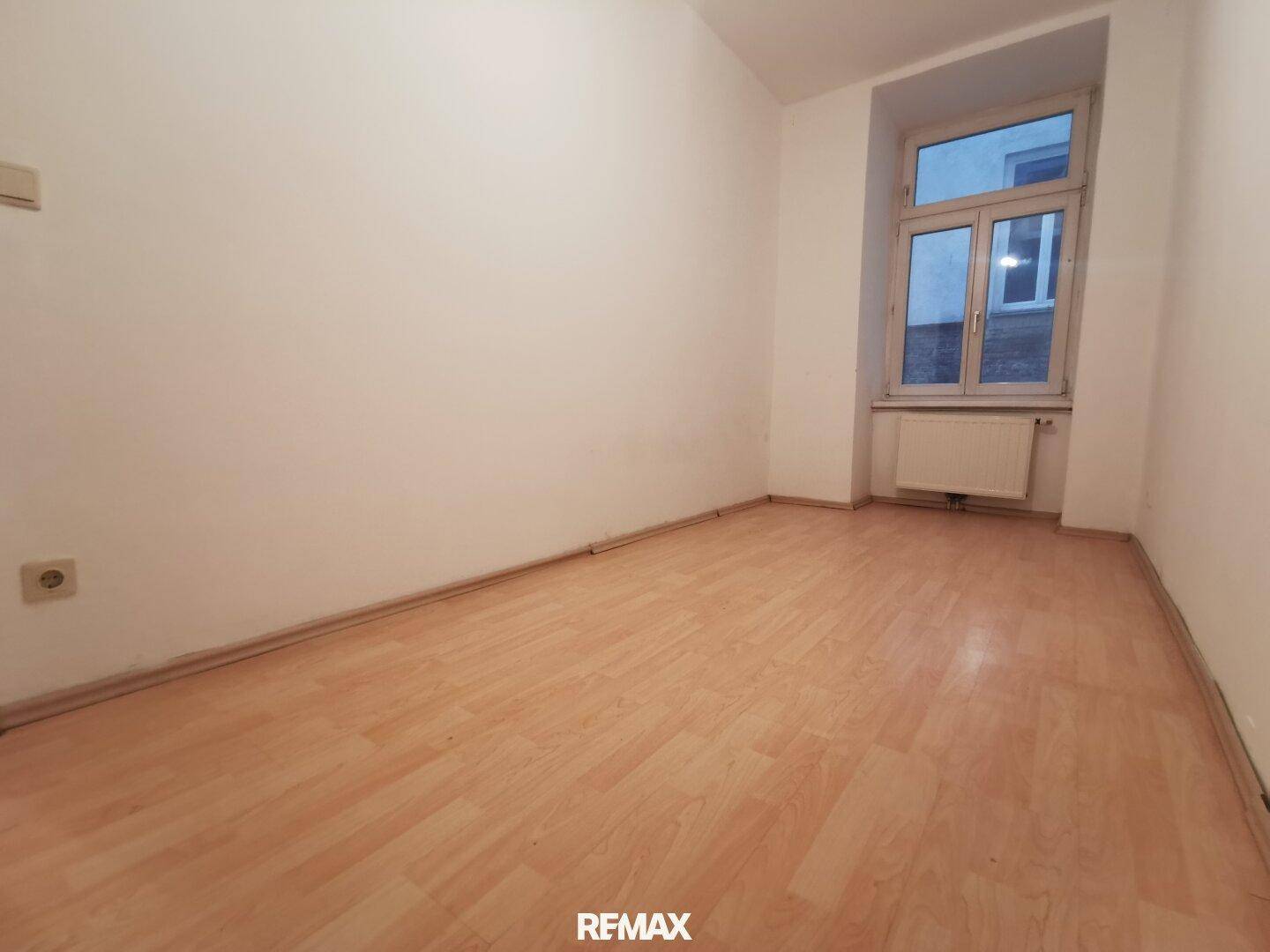 Kleiner, heller Raum mit Laminatboden und einem Fenster, ideal als Schlaf- oder Arbeitszimmer.