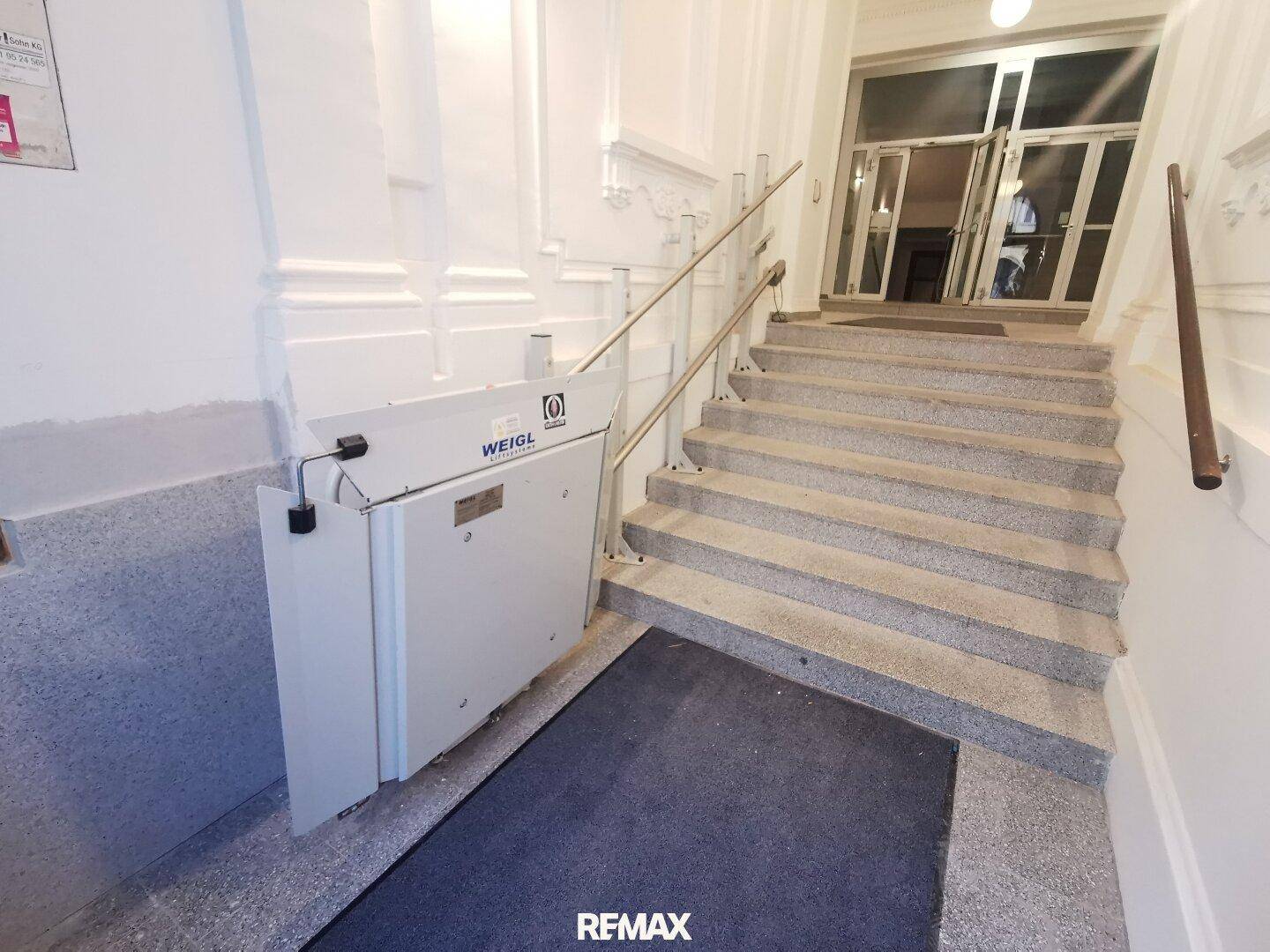 Treppenhaus mit Granitstufen und einem Treppenlift für barrierefreien Zugang.