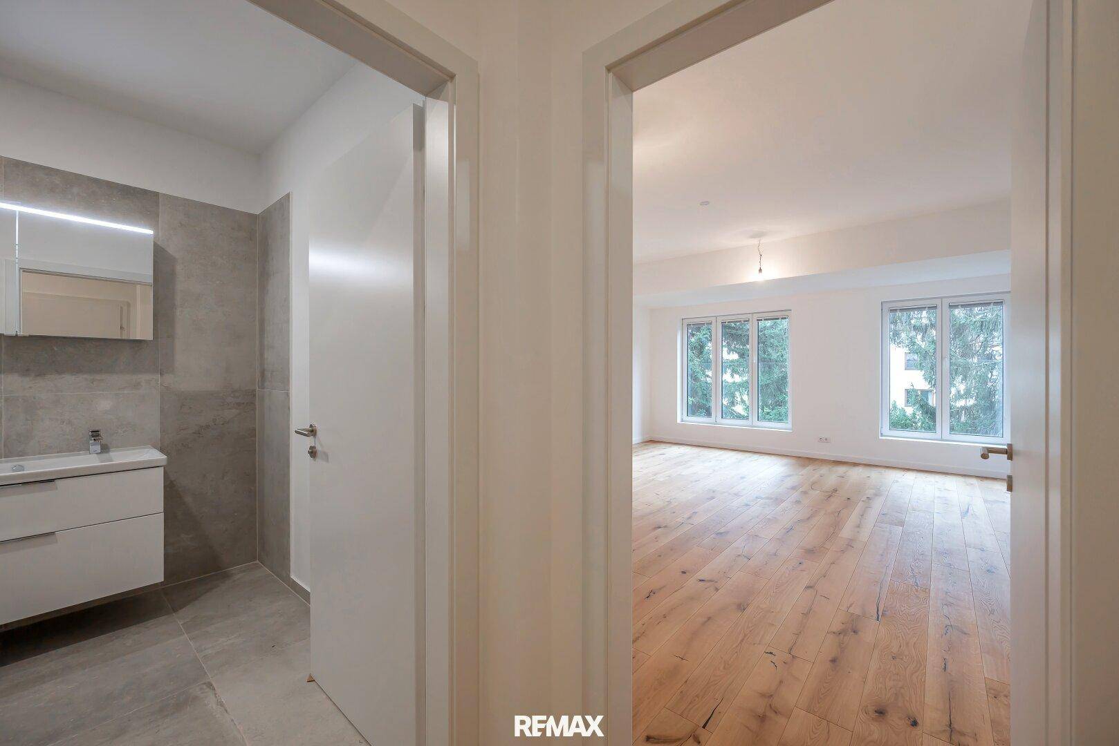 Heller Flur mit Holzboden, der zu einem Badezimmer und Wohnbereich führt.