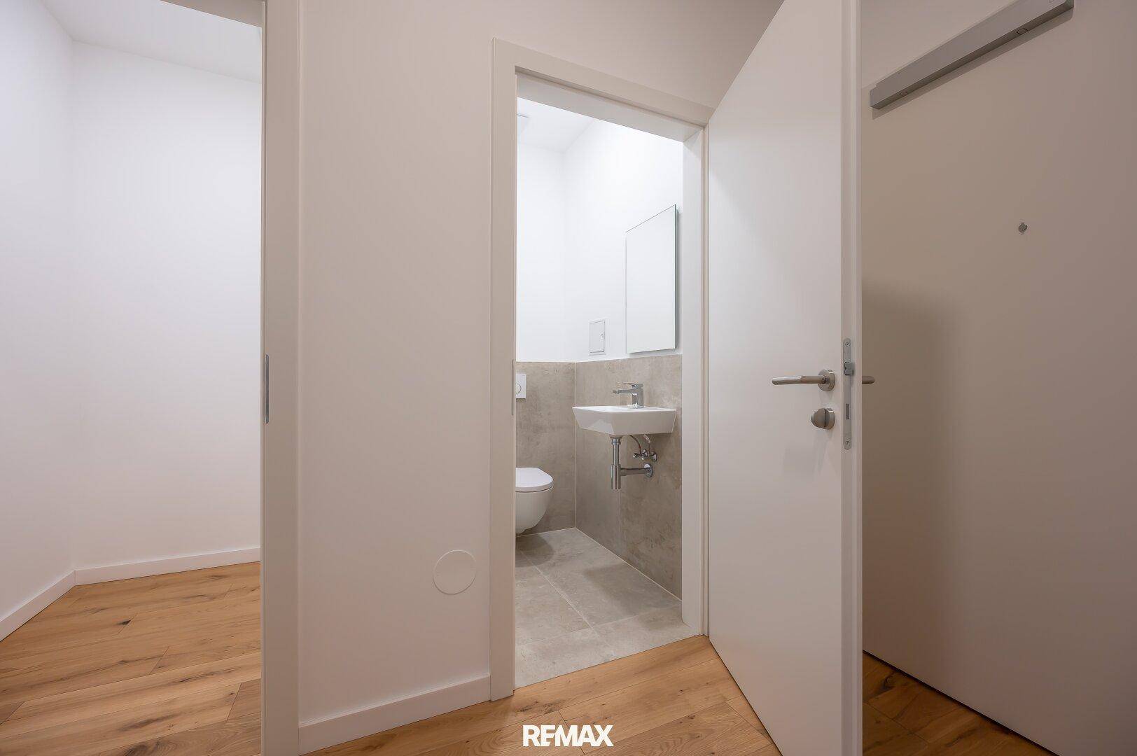 Separate Gästetoilette mit Wand-WC und kleinem Waschbecken.