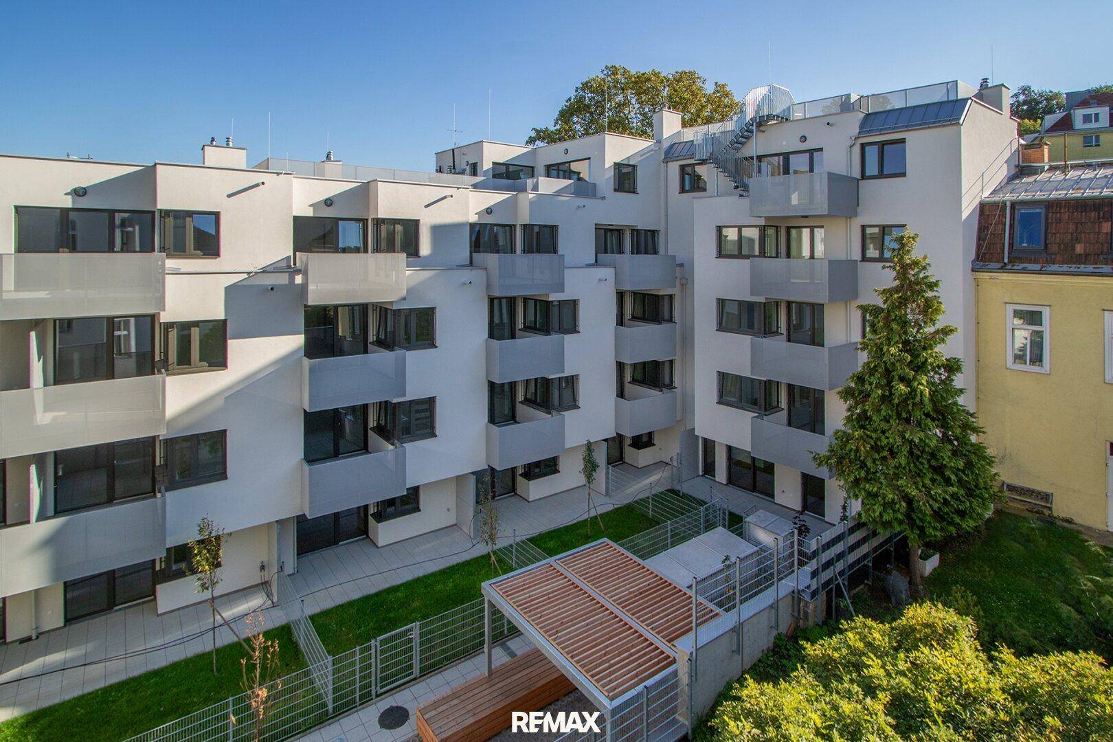 Moderne Wohnanlage mit mehreren Balkonen, gepflegtem Innenhof und grüner Umgebung.