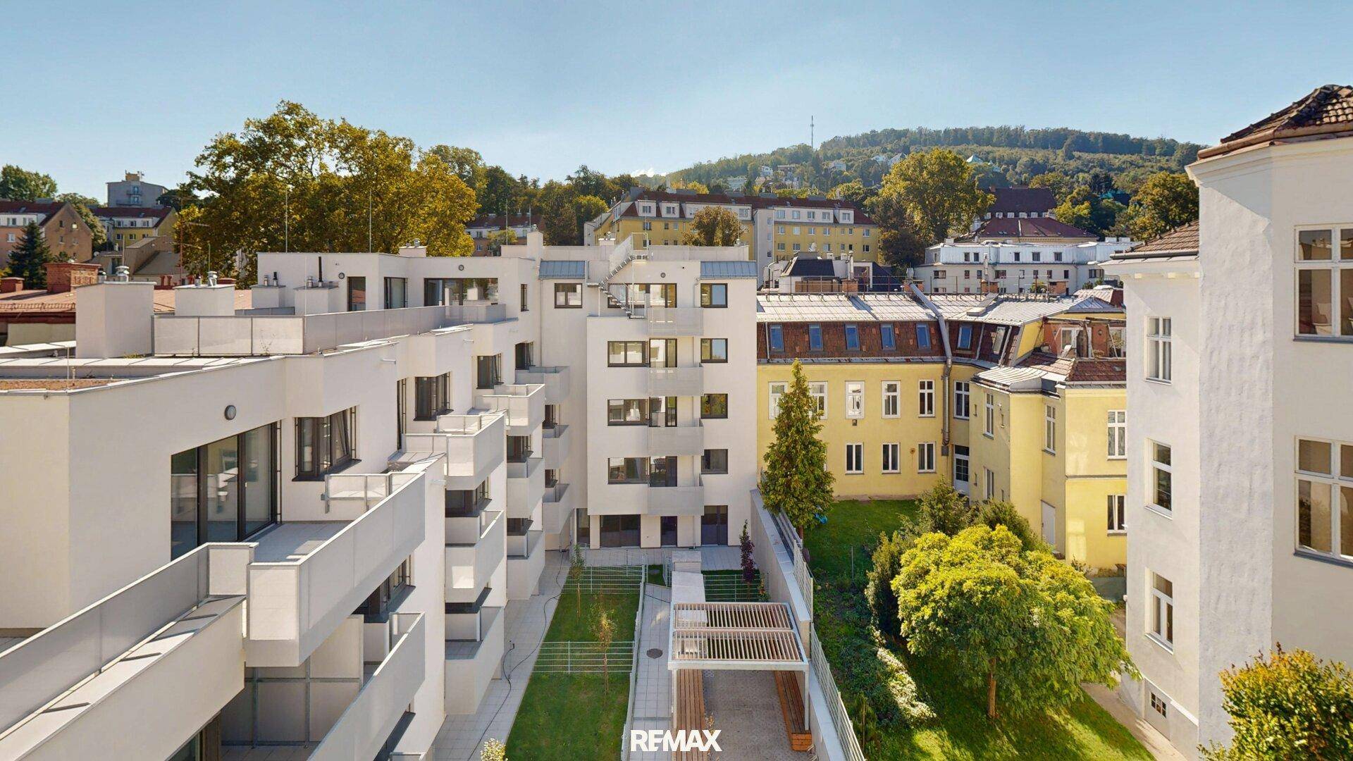 Moderner Wohnkomplex mit begrüntem Innenhof und umliegenden historischen Gebäuden.
