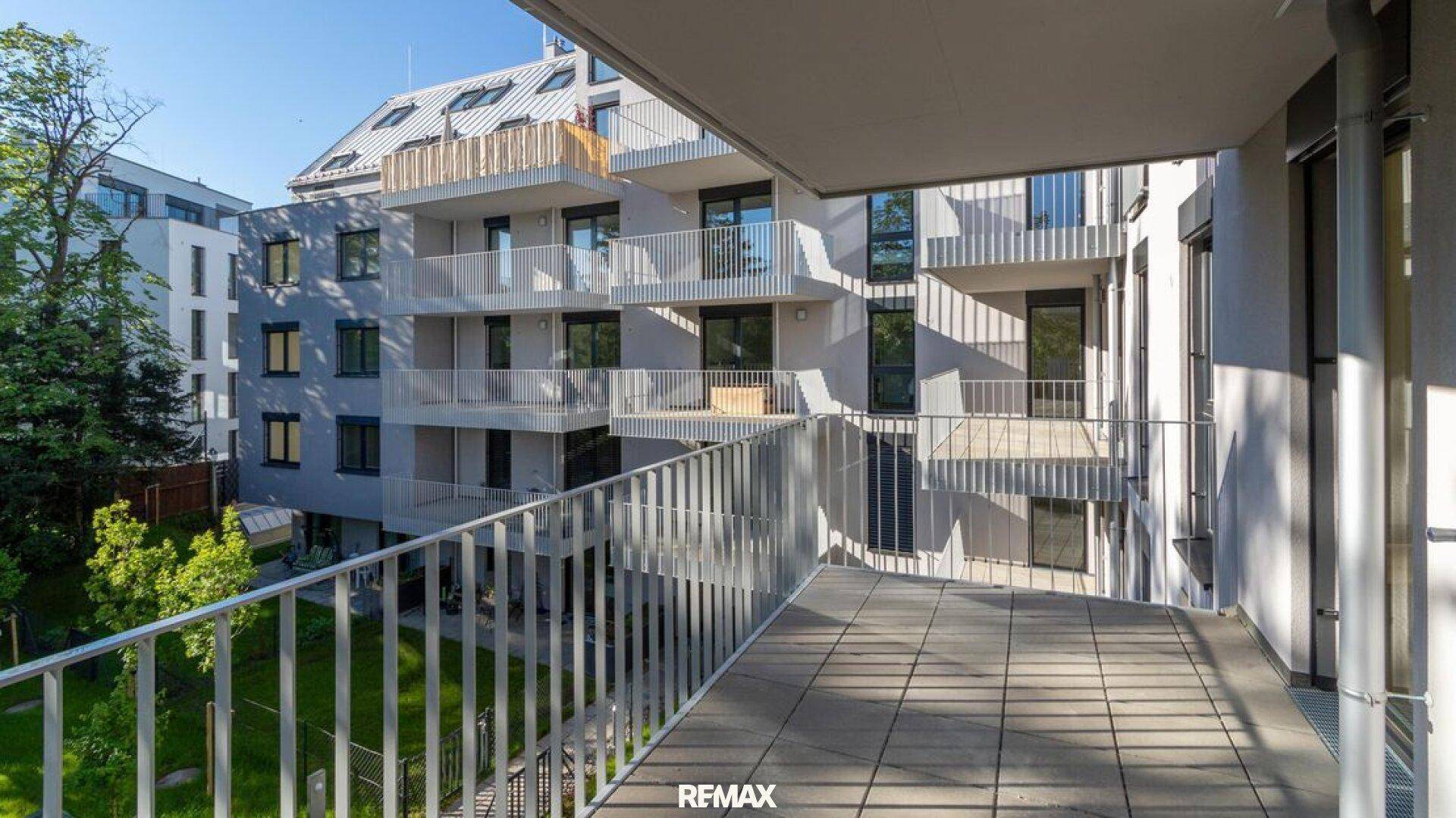 Balkon mit Blick auf die moderne Wohnanlage und den begrünten Innenhof.