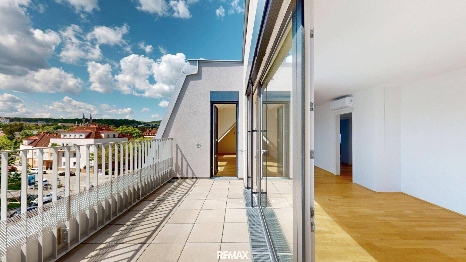 Großer Balkon mit Fliesenboden und Metallgeländer bietet einen weiten Blick über die Stadt.