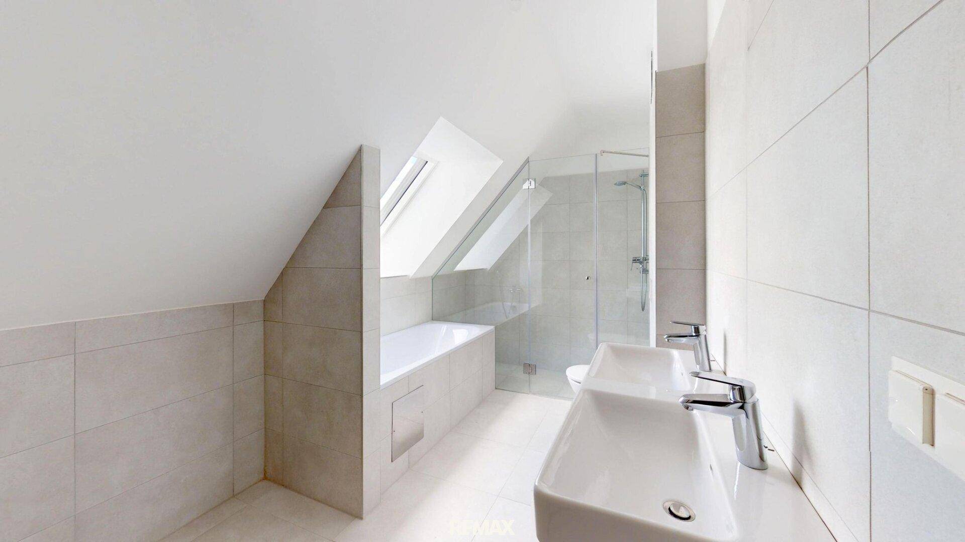 Modernes Badezimmer mit Badewanne, Dusche, Doppelwaschbecken und Dachfenstern unter der Schräge.