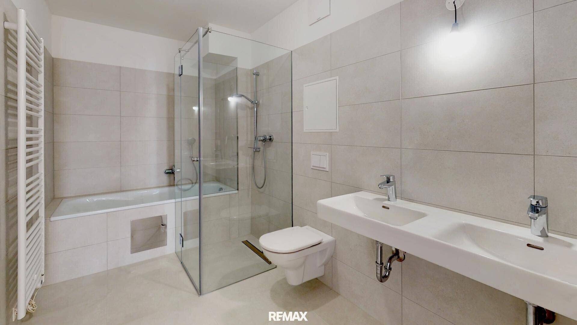 Modernes Badezimmer mit Dusche, Badewanne, Doppelwaschbecken und beheiztem Handtuchhalter.