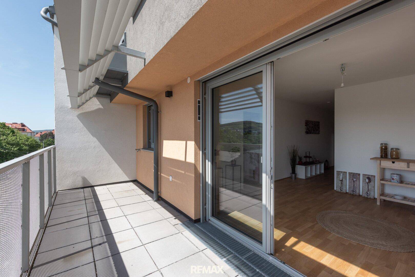 Geräumiger Balkon mit Fliesenboden und Blick ins Grüne, zugänglich vom Wohnbereich.