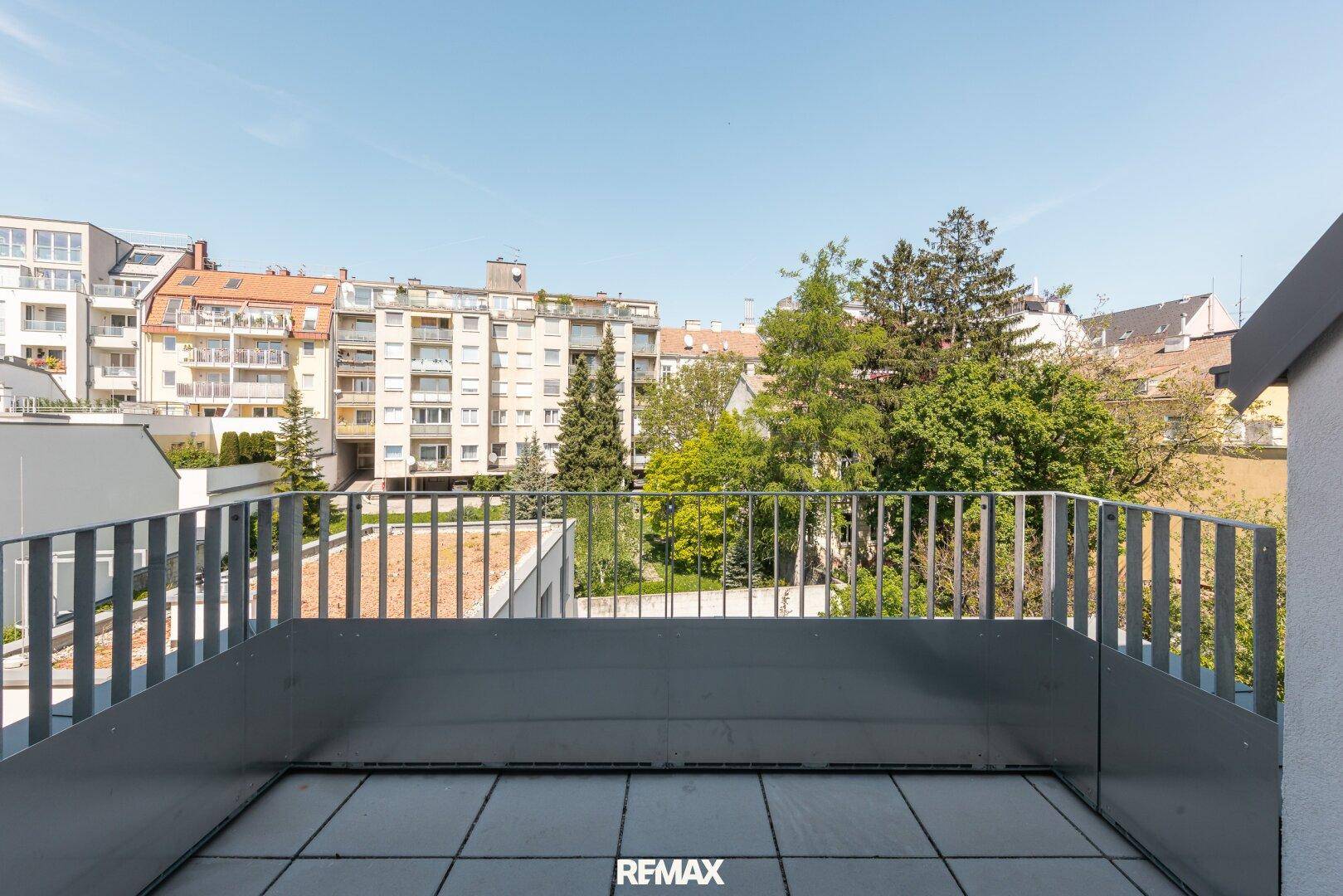 Geräumiger Balkon mit Fliesenboden und modernem Geländer, bietet einen weiten Blick auf die Stadt und umliegende Grünflächen.