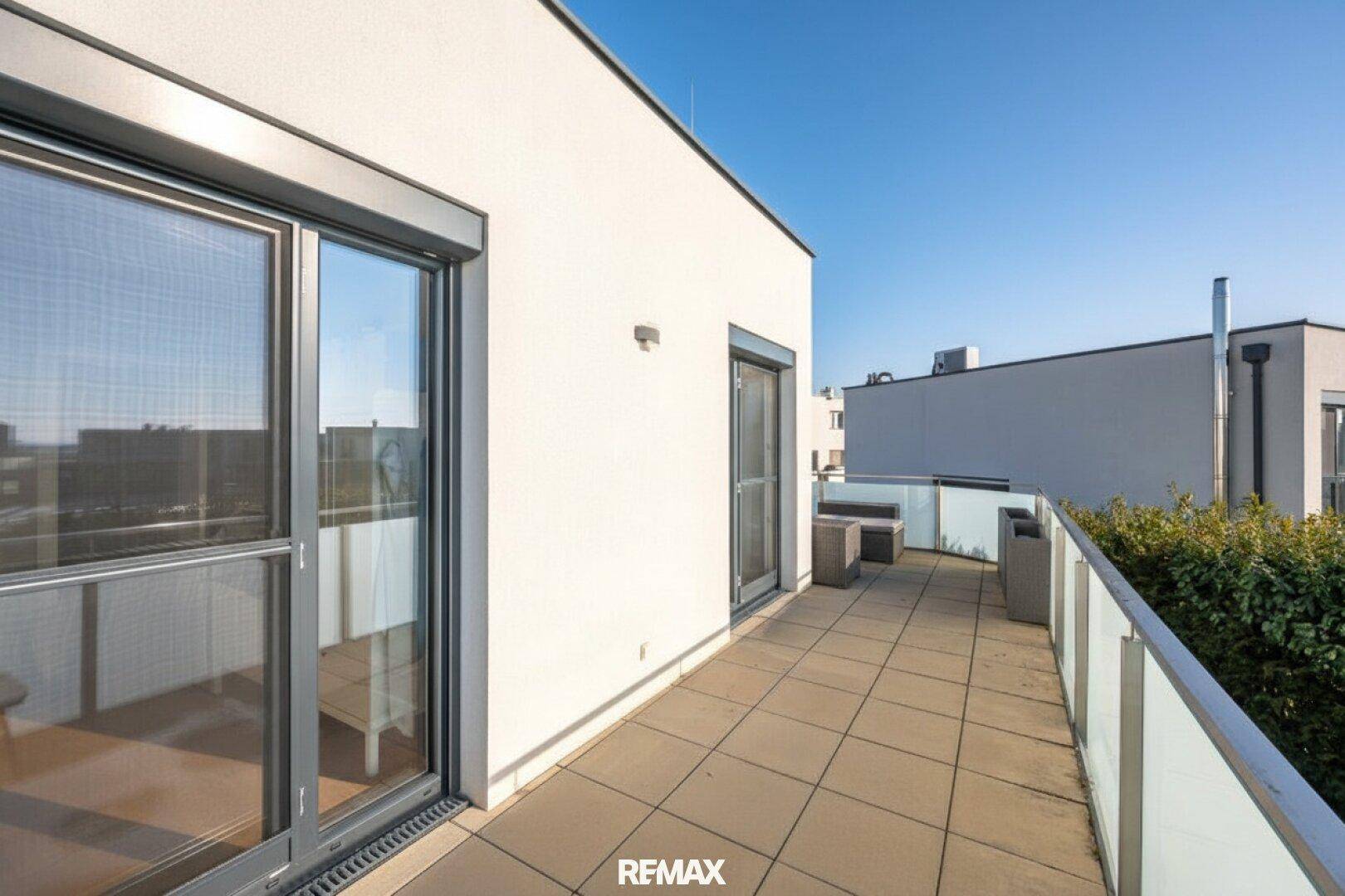 Großer Balkon mit Fliesenboden und Glasgeländer, ideal zum Entspannen im Freien.