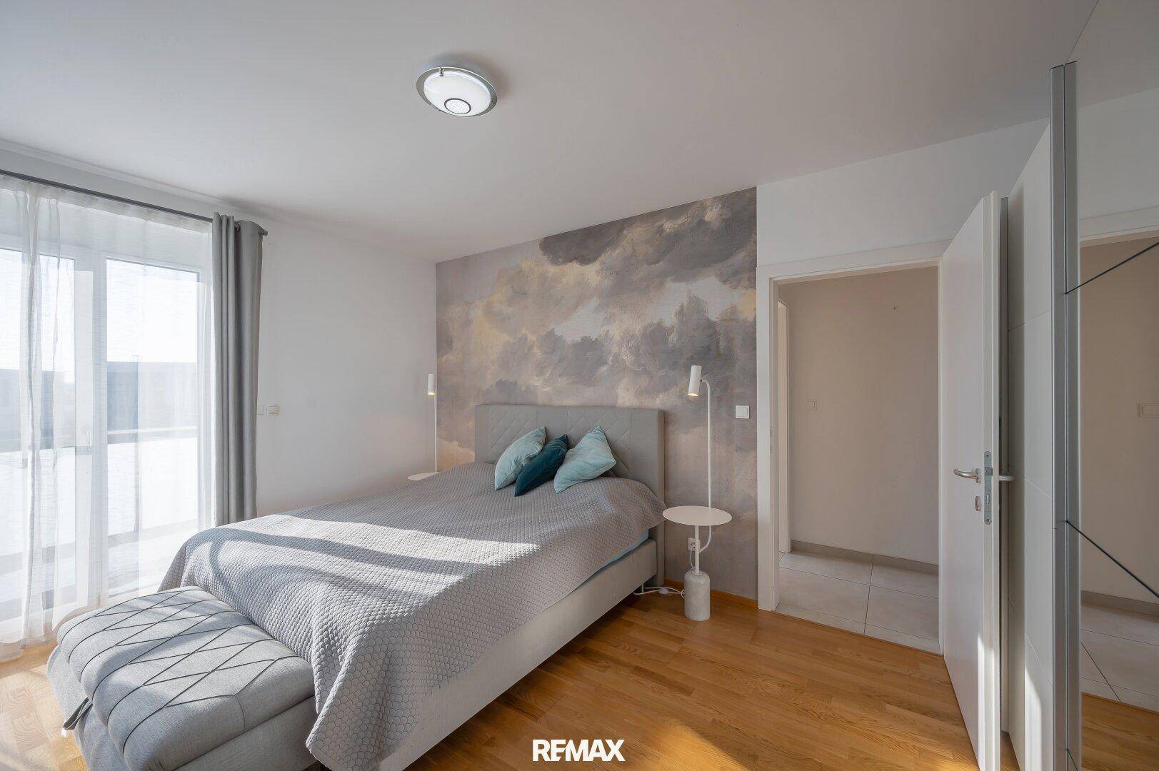 Helles Schlafzimmer mit Holzboden, modernem Bett und dekorativer Wandgestaltung.