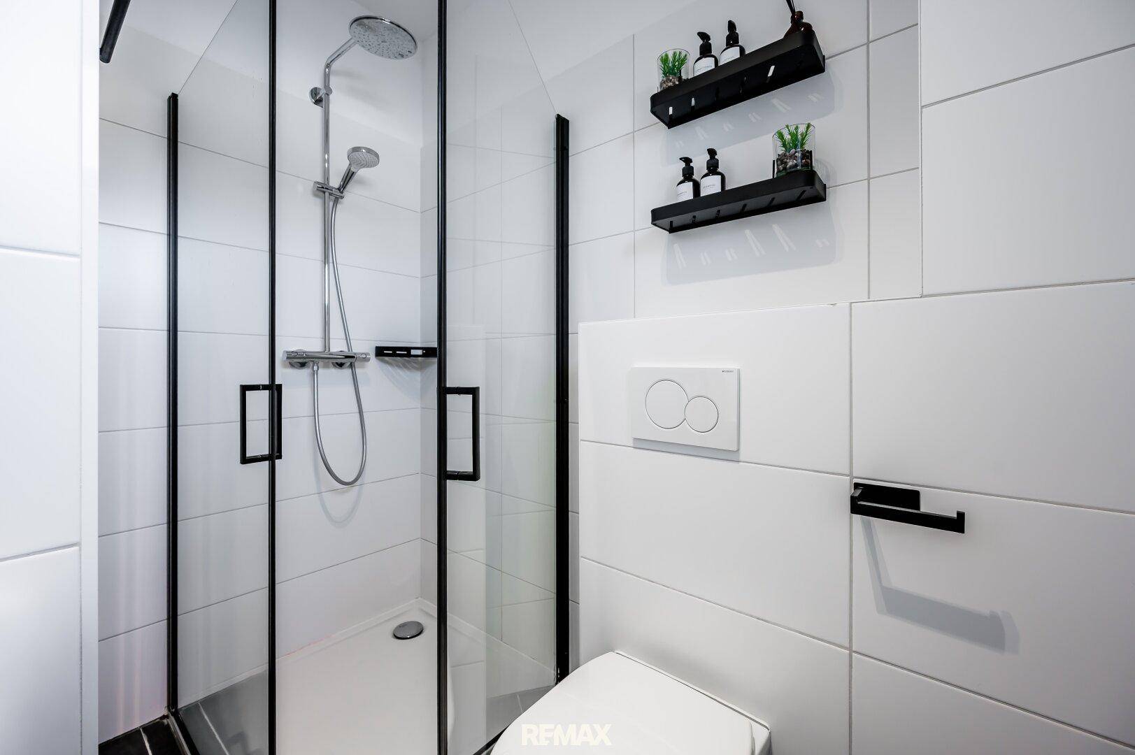 Kompaktes Gäste-WC mit moderner Duschkabine und Wand-WC.
