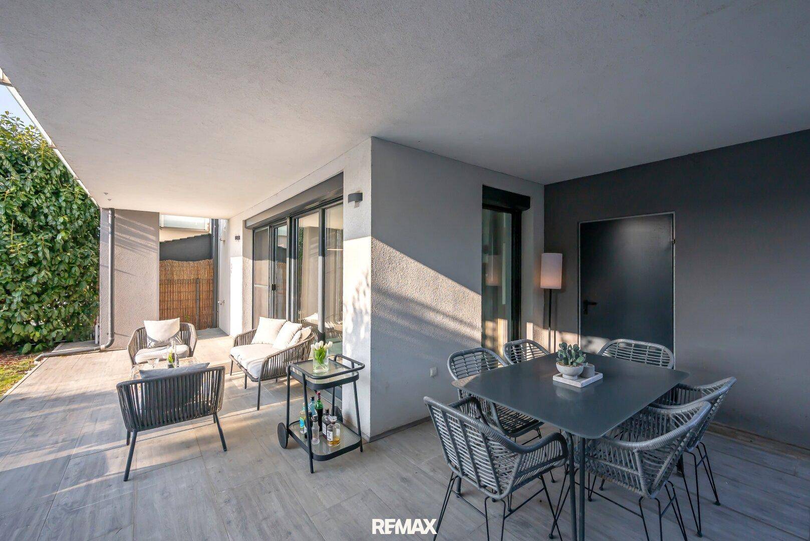 Geräumige überdachte Terrasse mit Essbereich und Lounge-Möbeln für entspannte Stunden.