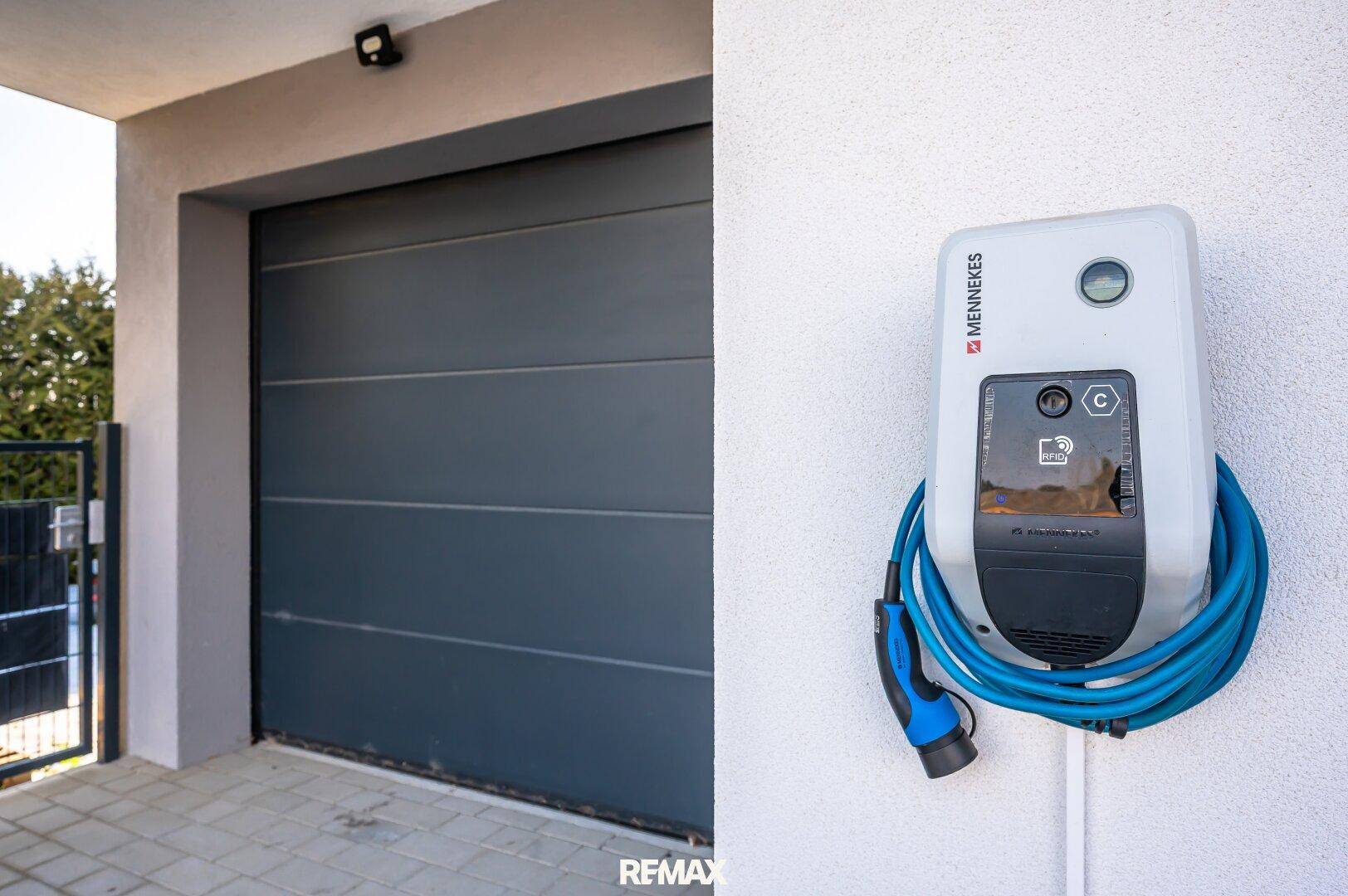 Moderne Garage mit Sektionaltor und Ladestation für Elektrofahrzeuge.