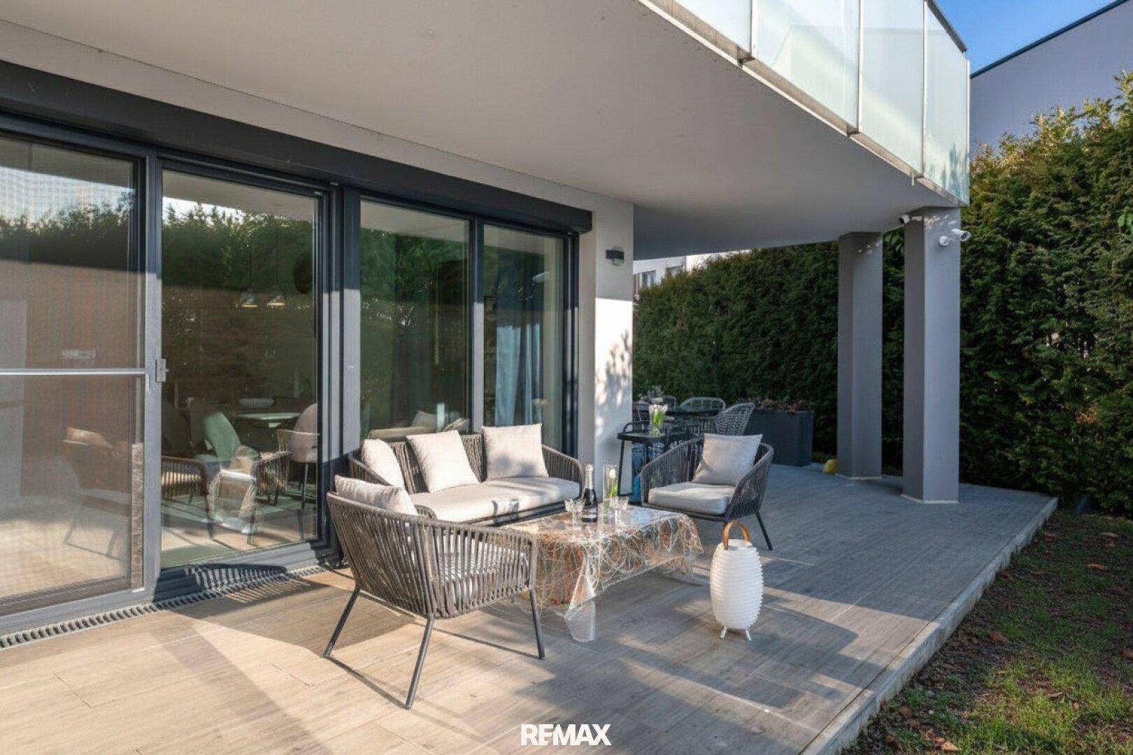 Überdachte Terrasse mit bequemen Lounge-Möbeln und Zugang zum Wohnbereich.
