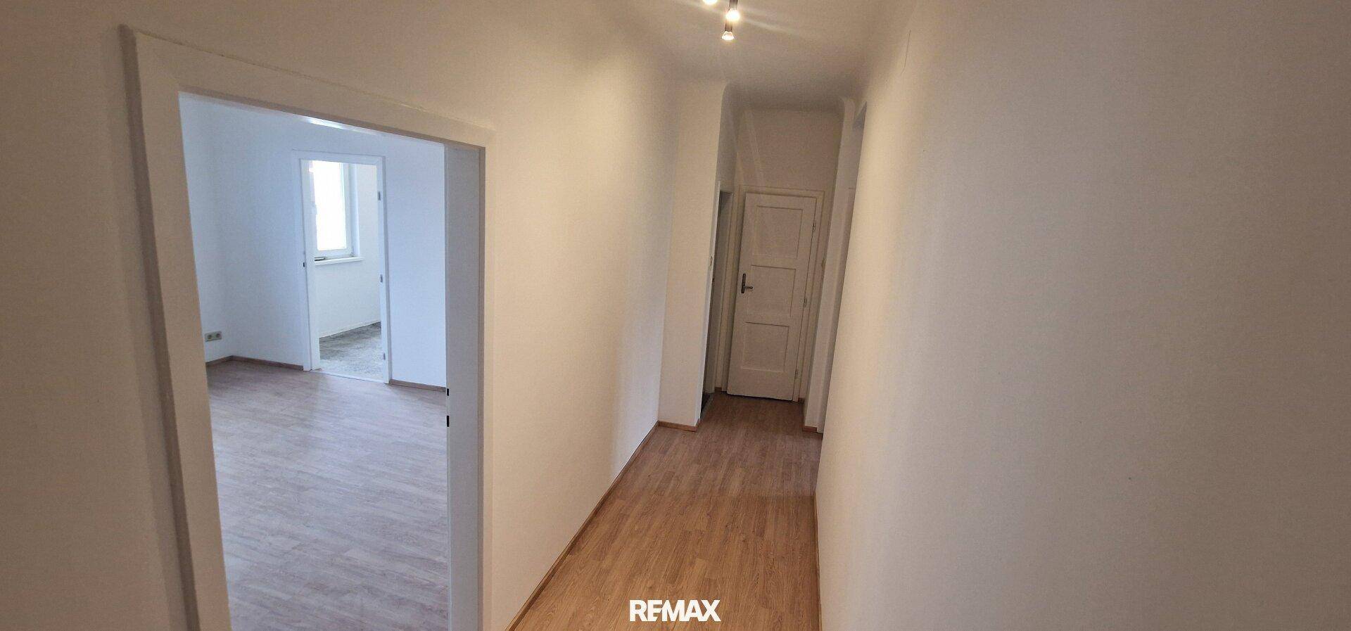 Langer Flur mit Holzboden, der zu den verschiedenen Zimmern der Wohnung führt.