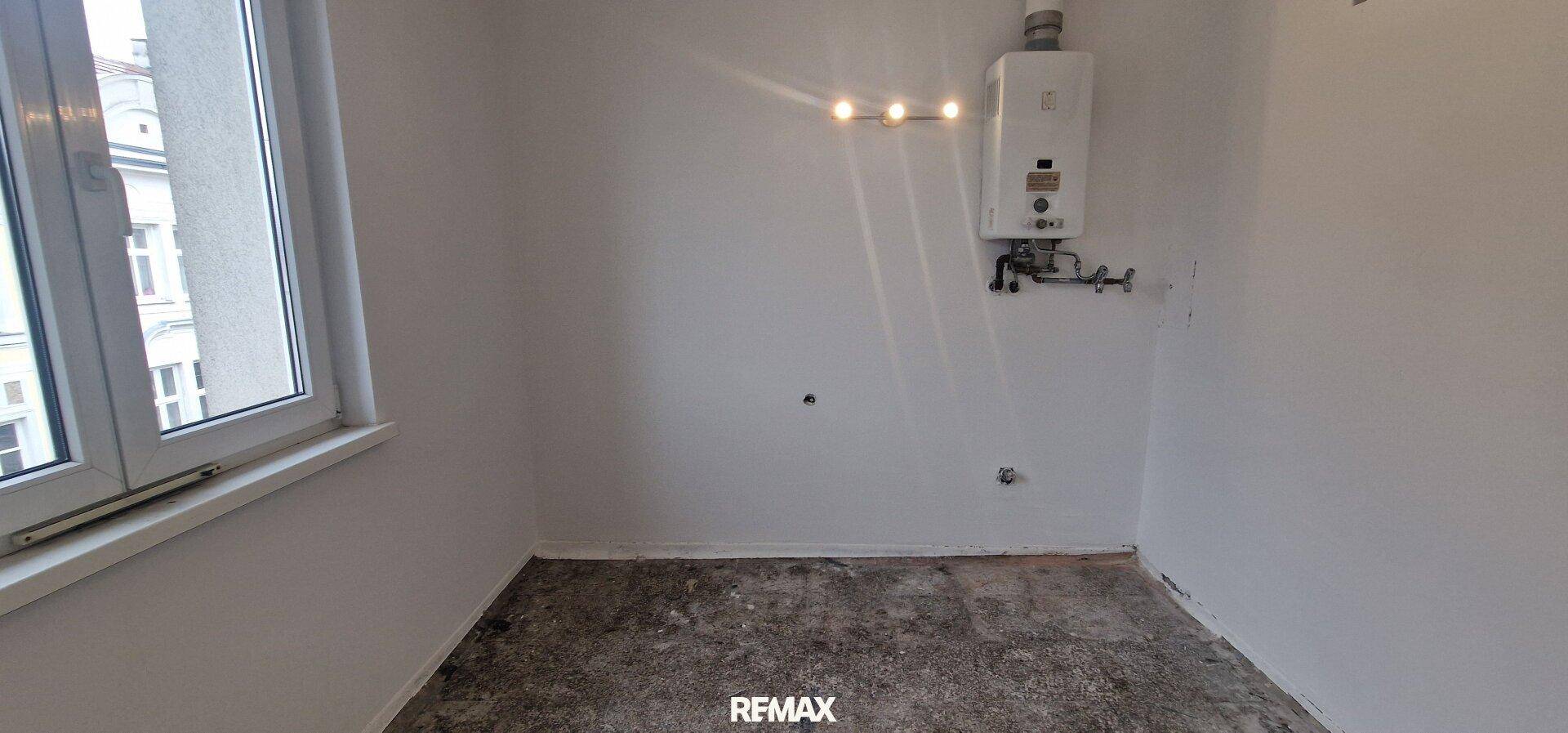 Raum mit Gastherme und Fenster, vorbereitet für eine Küche oder als Hauswirtschaftsraum.