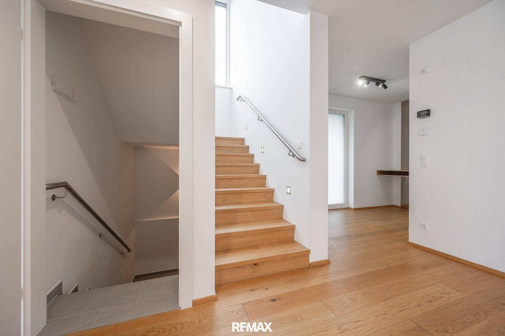 Elegante Holztreppe mit Handlauf, die in die obere Etage führt und von Tageslicht erhellt wird.