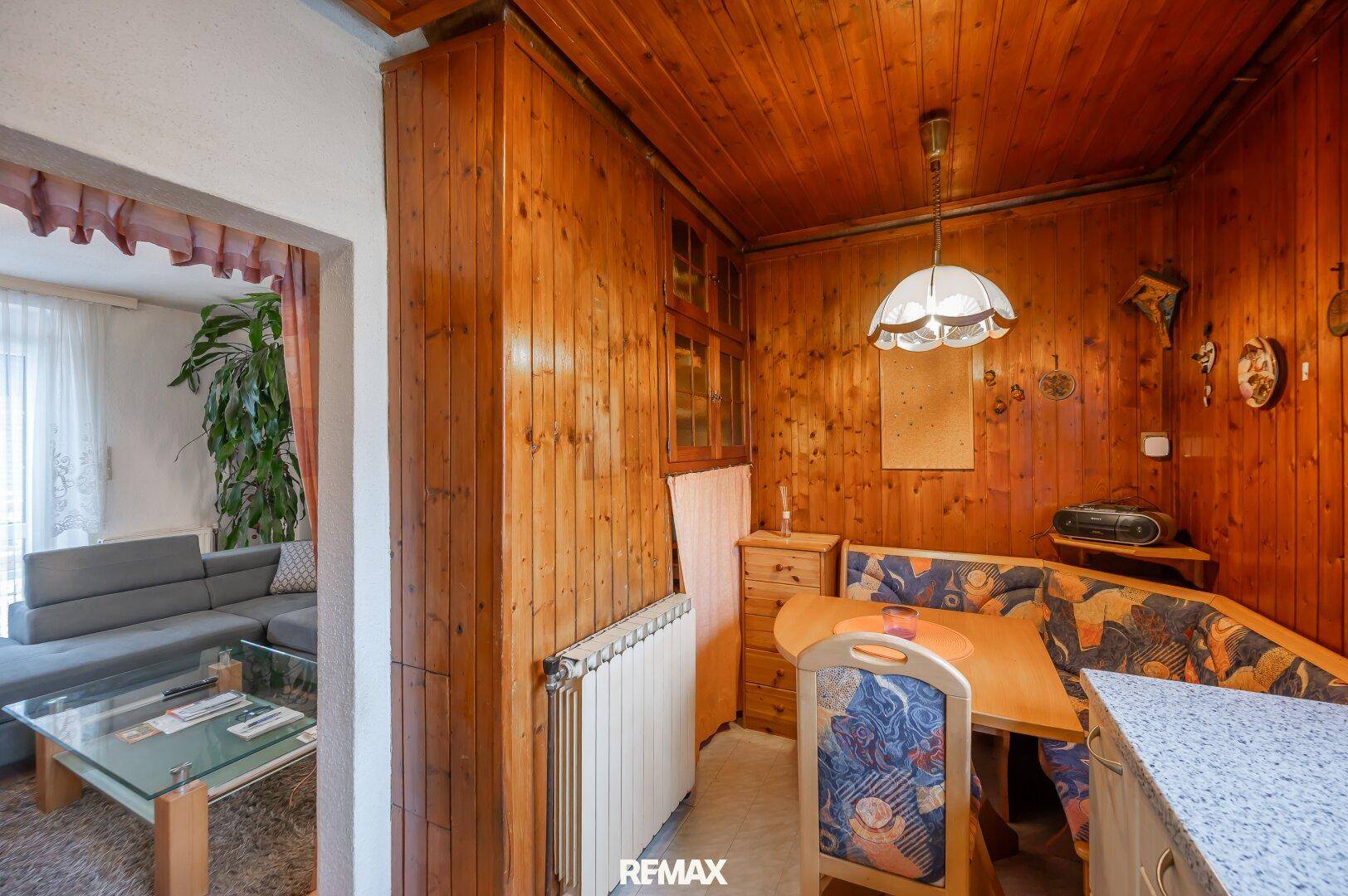 Gemütliche Essecke mit Holzverkleidung und Blick in das angrenzende Wohnzimmer, ideal für Mahlzeiten.
