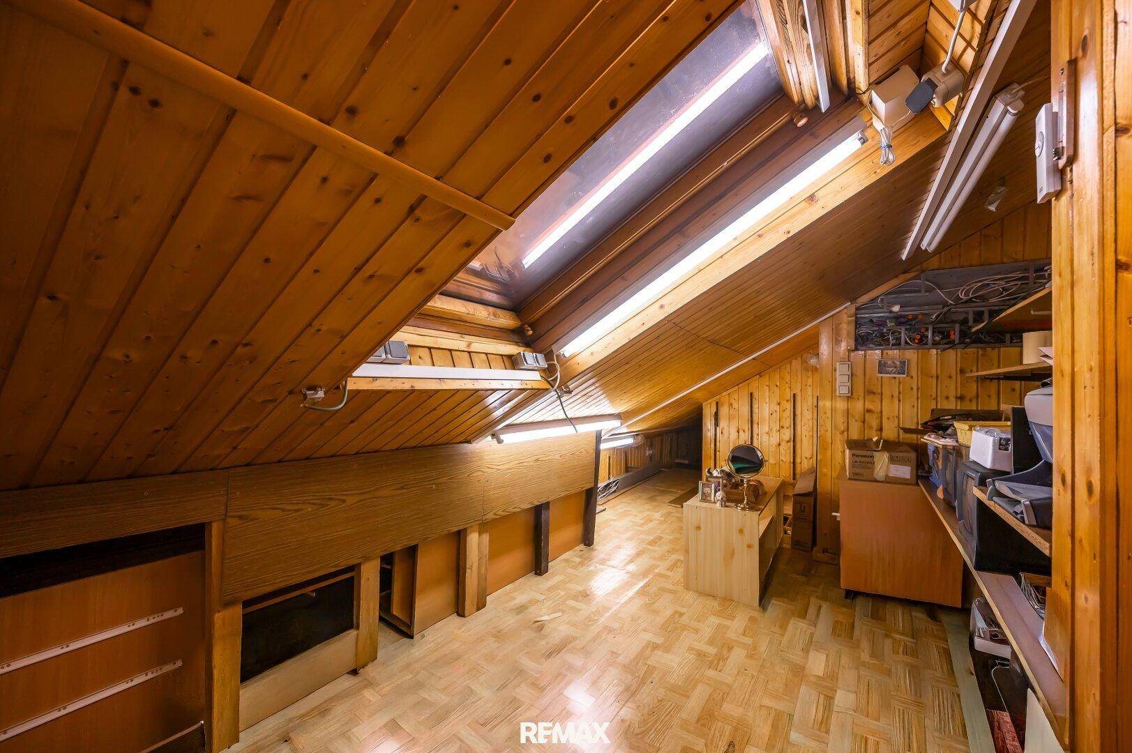 Geräumiger Dachboden mit Holzverkleidung, sichtbaren Balken und Oberlichtern, ideal als Stauraum.