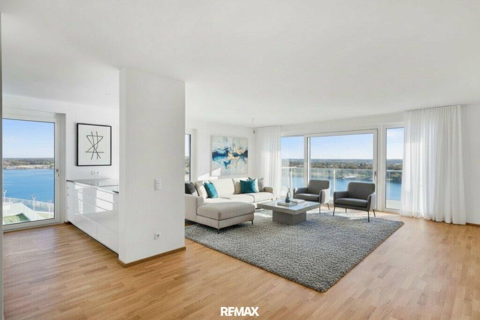 Offener Wohnbereich mit Holzboden, modernen Möbeln und großen Fenstern mit Panoramablick auf den See.